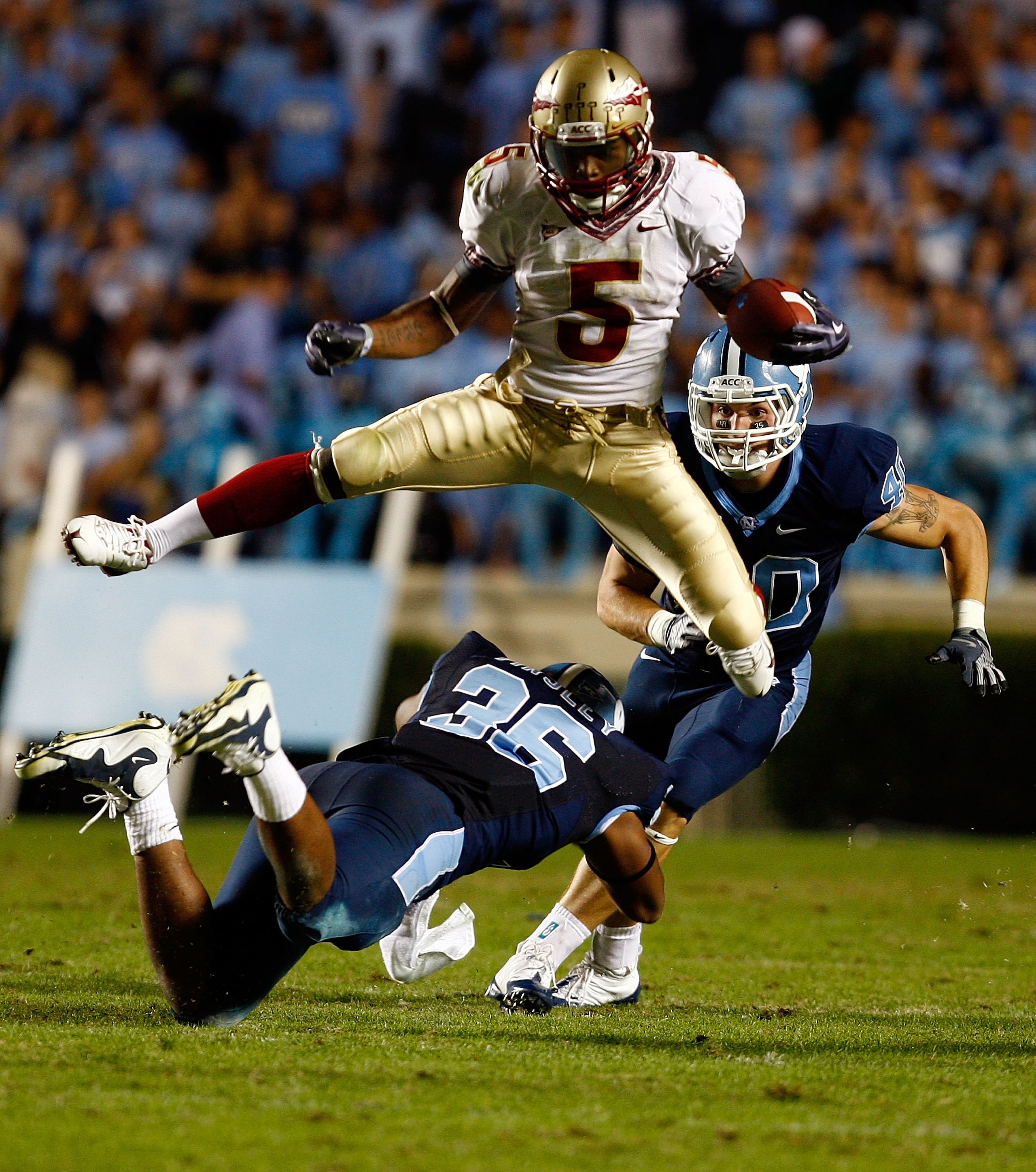CHAPEL HILL, NC - OCTOBER 22:  Greg Reid #5 of the Florida State Seminoles leaps over North Carolina Tar Heels defenders Kennedy Tinsley #36 and Hunter Furr, #40 at Kenan Stadium on October 22, 2009 in Chapel Hill, North Carolina.  (Photo by Scott Hallera