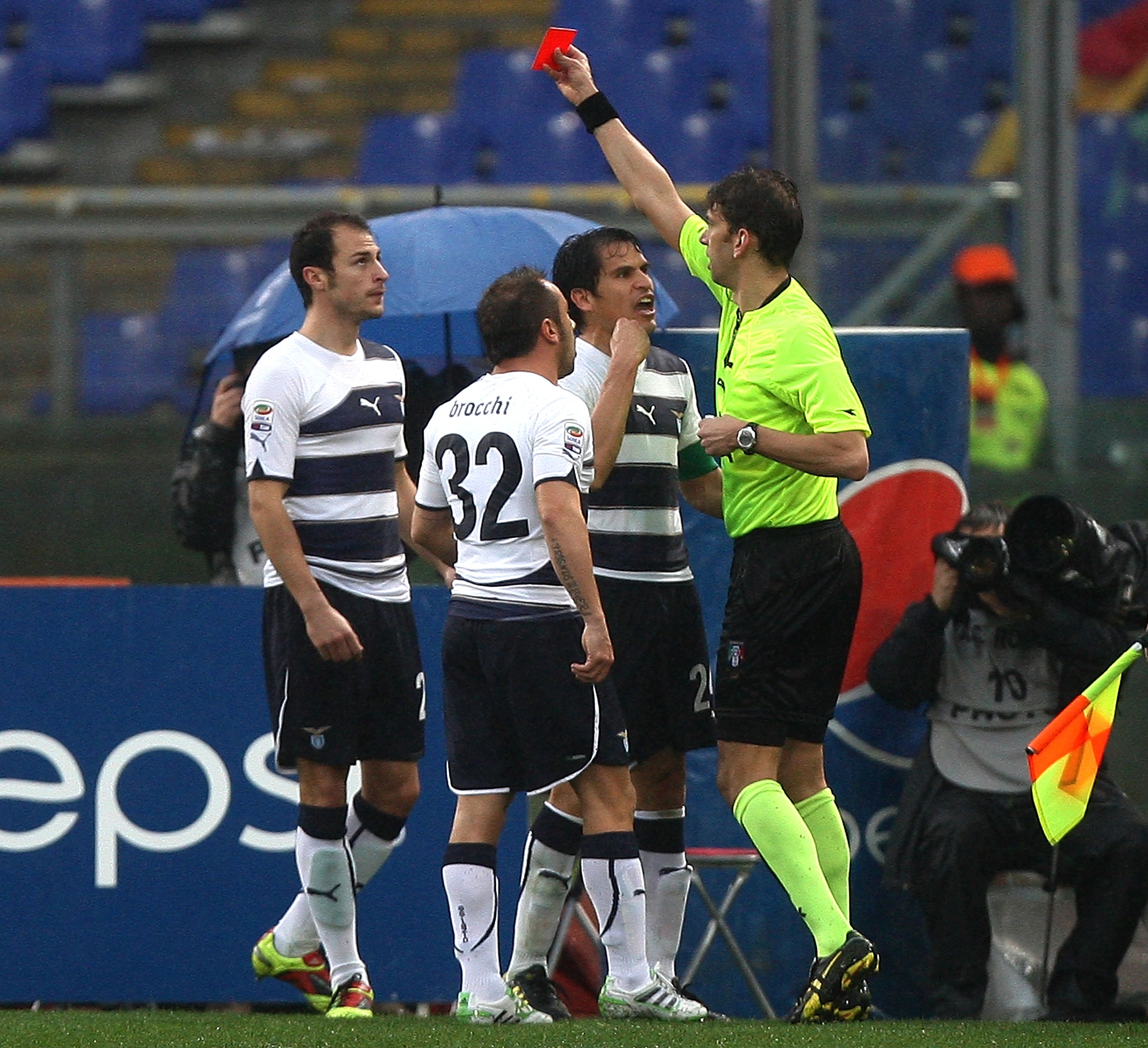 ROME, ITALY - MARCH 13:  The referee Paolo Tagliavento shows the red card to Stephan Radu (L) of SS Lazio as his teammates Cristian Brocchi #32 and Cristian Ledesma (2ndR) react during Serie A match between AS Roma and SS Lazio at Stadio Olimpico on March