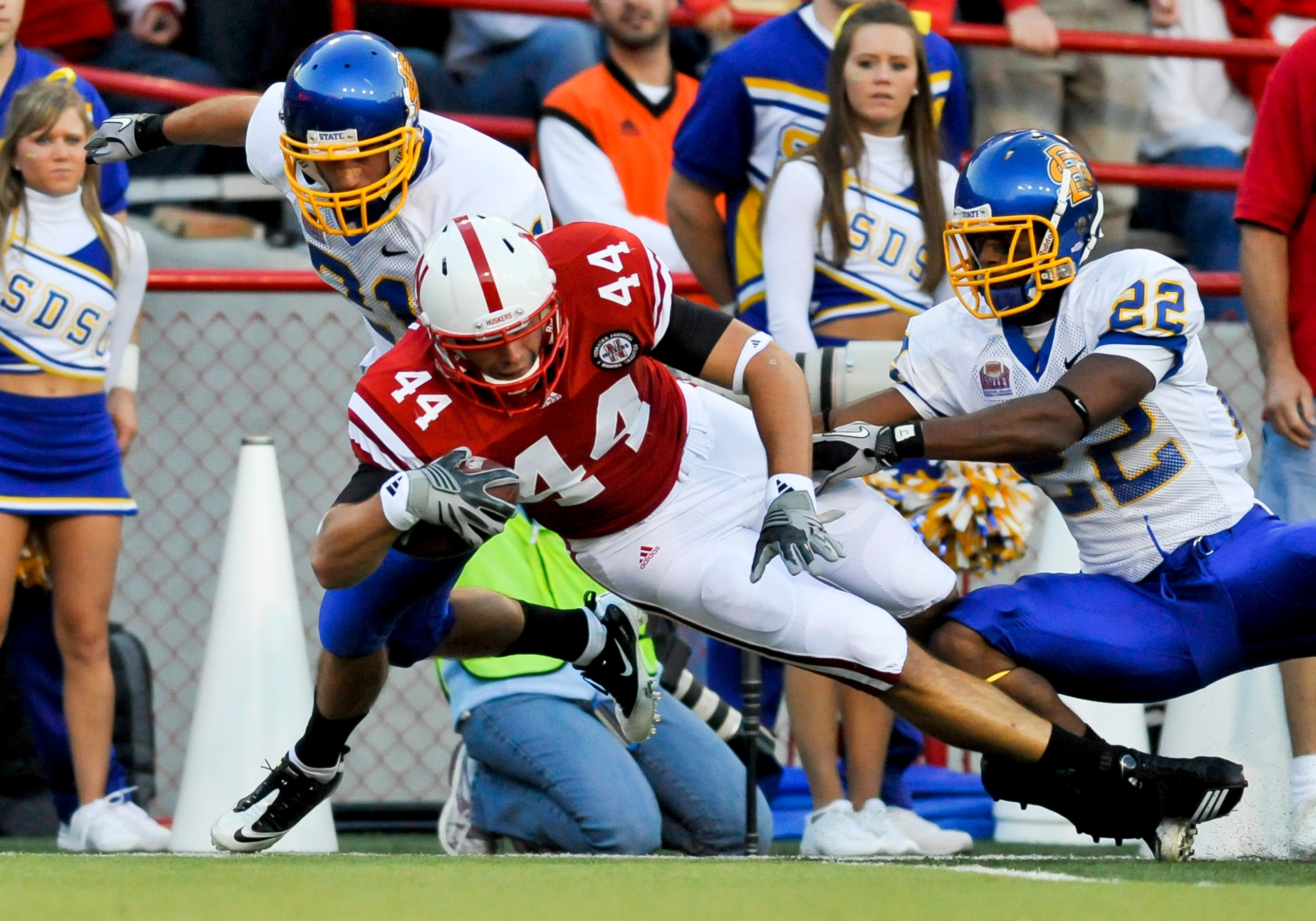 LINCOLN, NEBRASKA - SEPTEMBER 25: Nebraska Cornhuskers tight end Mike McNeill #44 gets knocked down by South Dakota State Jackrabbits cornerback Anthony Wise #22 and cornerback Cole Brodie #21 during first half action of their game at Memorial Stadium on