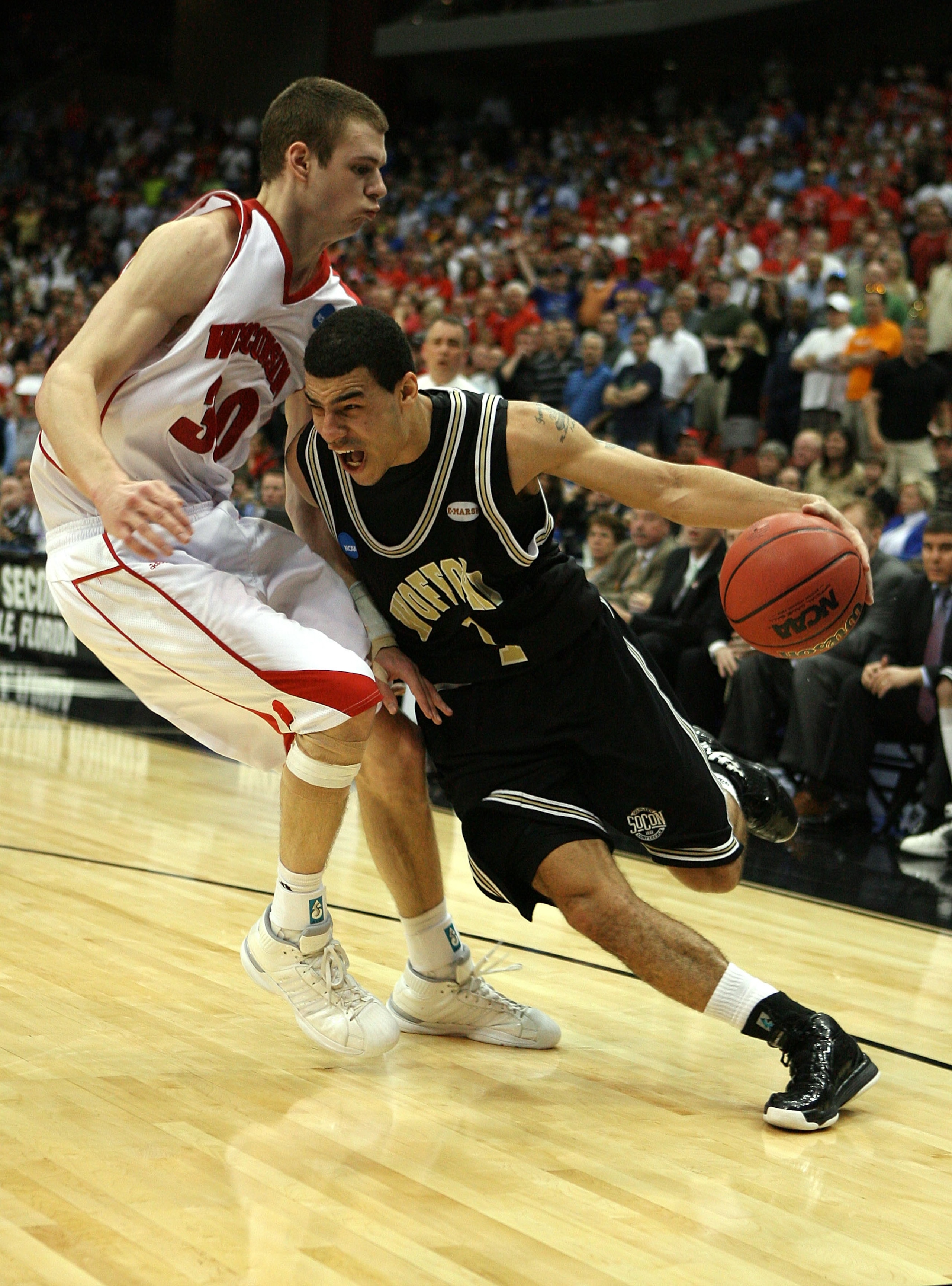JACKSONVILLE, FL - MARCH 19:  Cameron Rundles #1 of the Wofford Terriers tries to drive around Jon Leuer #30 of the Wisconsin Badgers in the first round of the 2010 NCAA men's basketball tournament at Jacksonville Veteran's Memorial Arena on March 19, 201