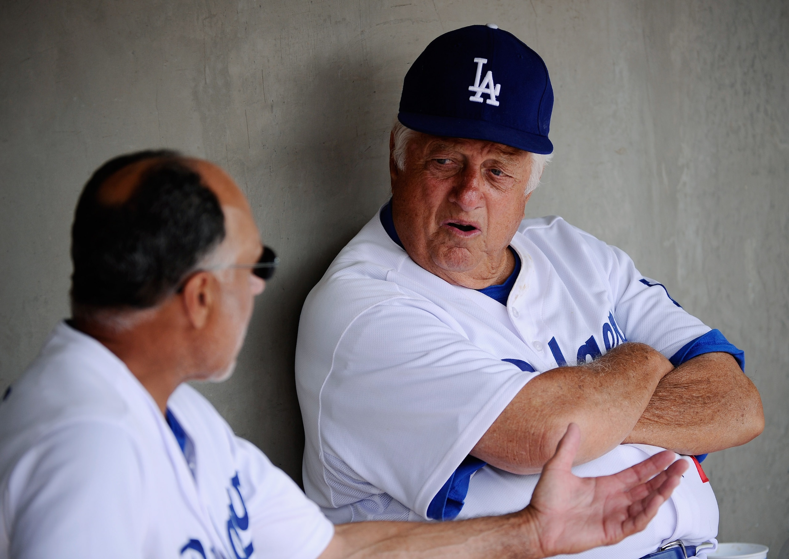 GLENDALE, AZ - MARCH 15:  Hall of Fame manager Tommy Lasorda #2 of the Los Angeles Dodgers speaks first base coach and Davey Lopes in the dugout prior to the start of the spring training baseball game against the Texas Rangers at Camelback Ranch on March 