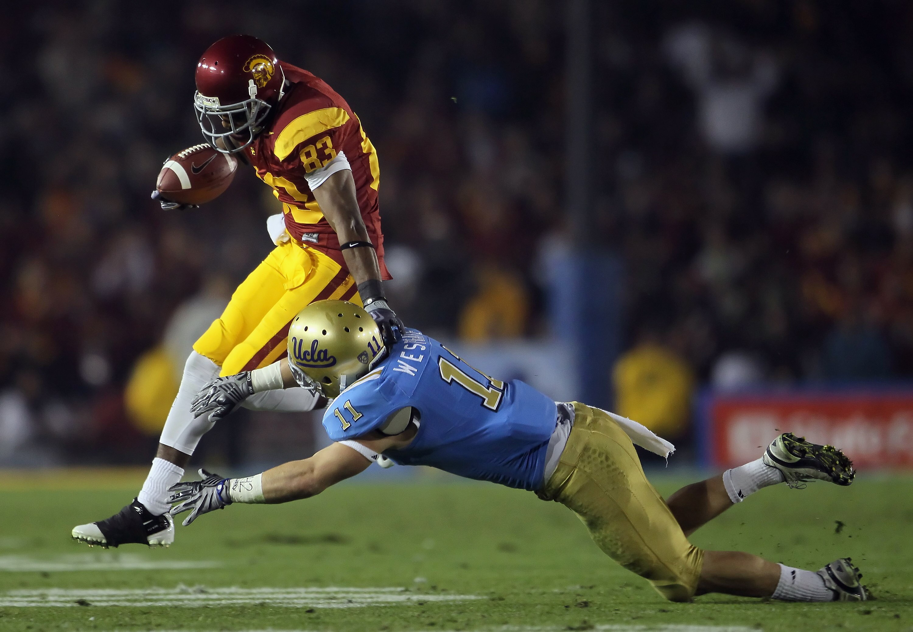 PASADENA, CA - DECEMBER 04:  Wide receiver Ronald Johnson #83 of the USC Trojans breaks a tackle by Sean Westgate #11 of the UCLA Bruins during the first half at the Rose Bowl on December 4, 2010 in Pasadena, California. USC defeated UCLA 28-14.  (Photo b