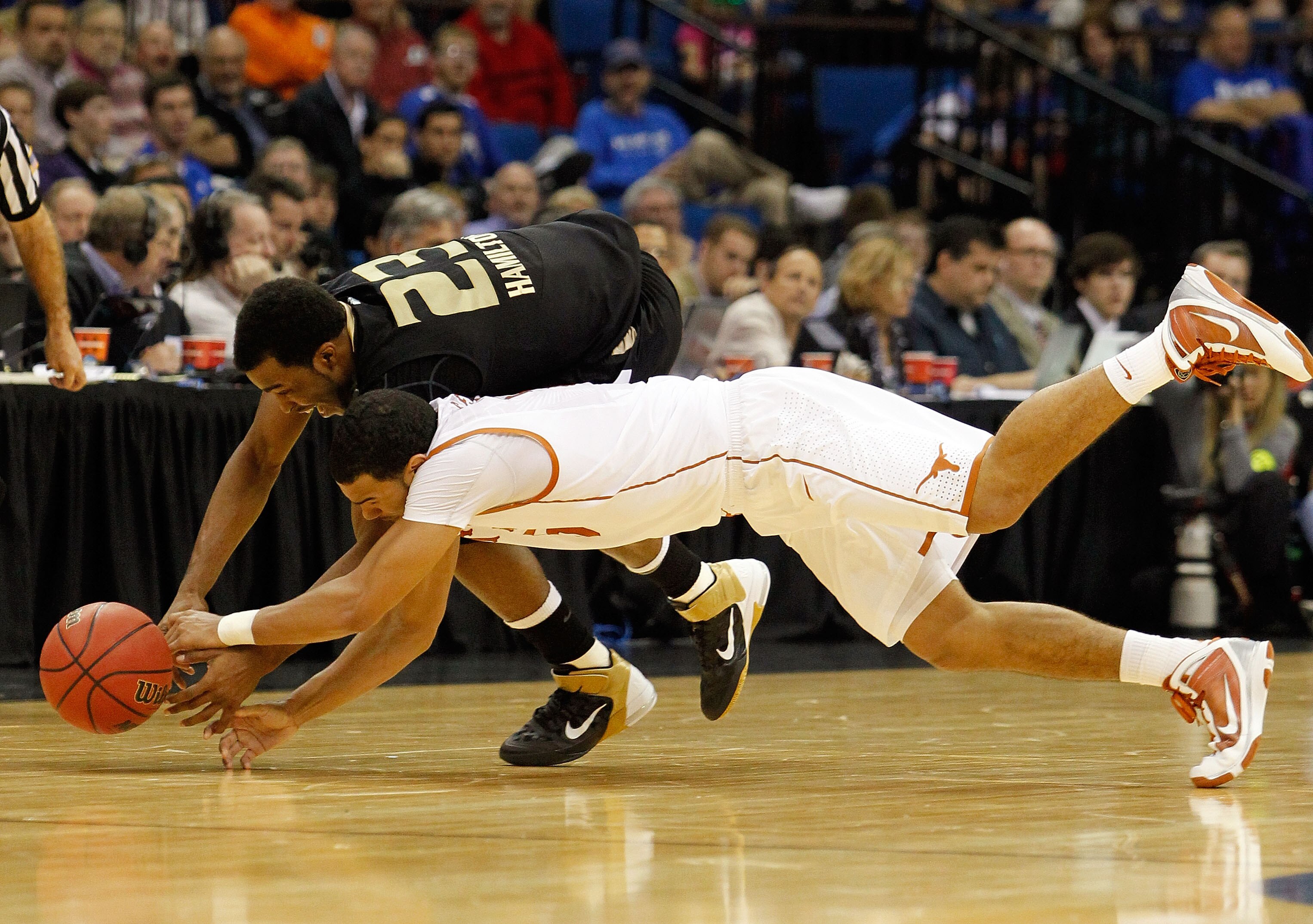 TULSA, OK - MARCH 18:  Reggie Hamilton #23 of the Oakland Golden Grizzlies and Cory Joseph #5 of the Texas Longhorns dive for a loose ball during the second round of the 2011 NCAA men's basketball tournament at BOK Center on March 18, 2011 in Tulsa, Oklah