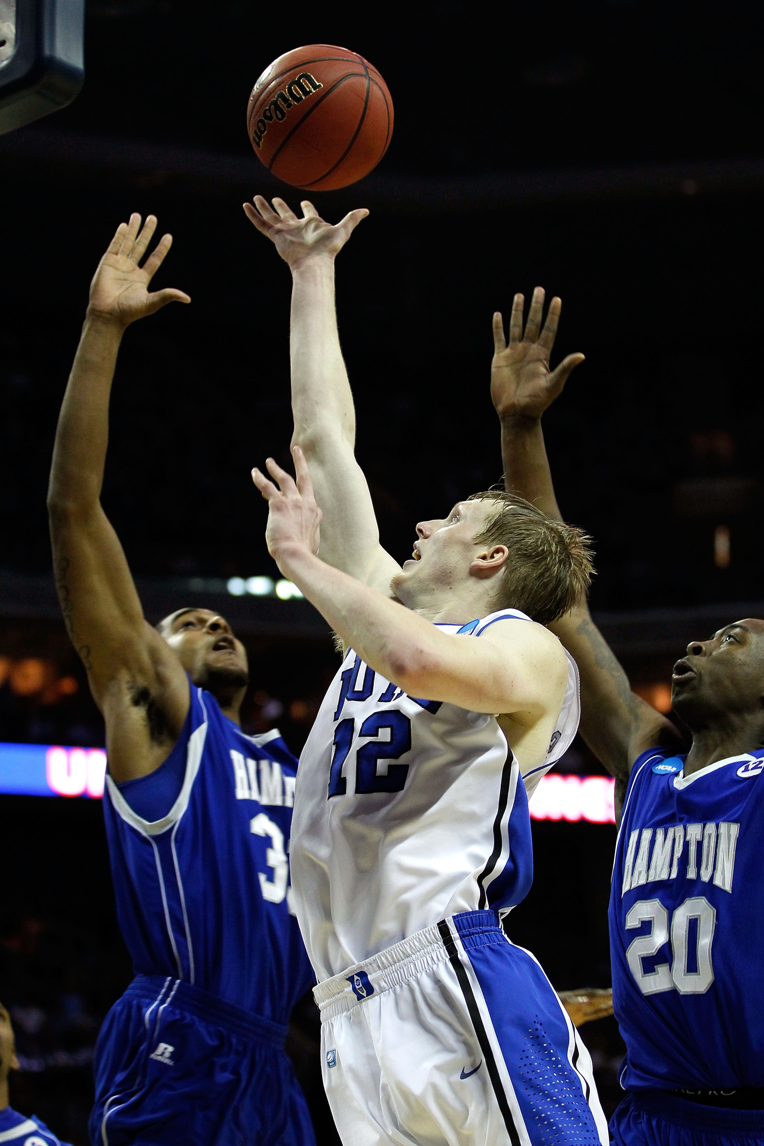 CHARLOTTE, NC - MARCH 18:  Kyle Singler #12 of the Duke Blue Devils shoots the ball between Koron Reed #33 and Charles Funches #20 of the Hampton Pirates in the first half during the second round of the 2011 NCAA men's basketball tournament at Time Warner