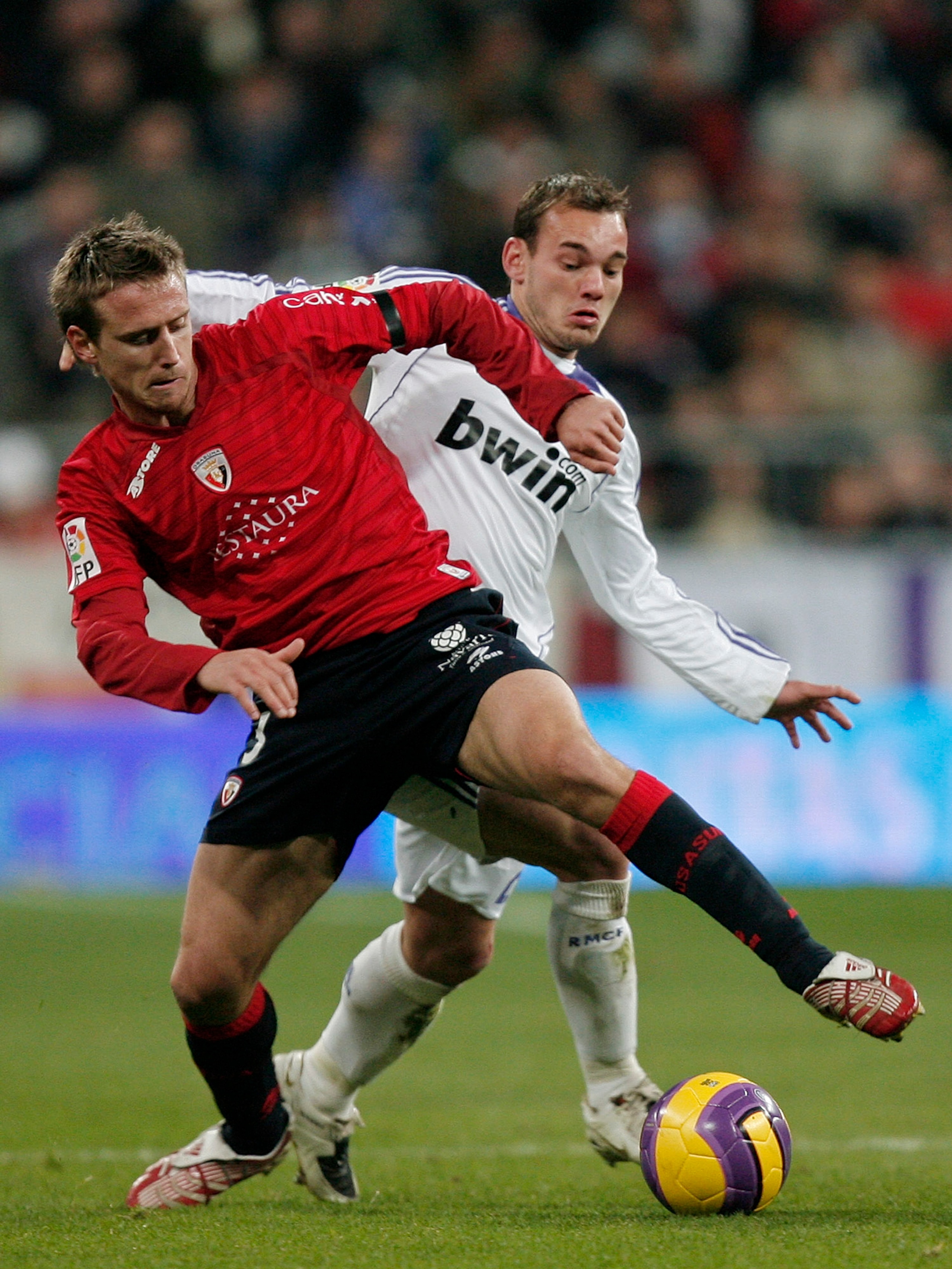 MADRID, SPAIN - DECEMBER 16:  Wesley Sneijder (R) of Real Madrid duels for the ball with Ignacio Monreal of Osasuna during the La Liga match between Real Madrid and Osasuna at the Santiago Bernabeu Stadium on December 16, 2007 in Madrid, Spain.  (Photo by