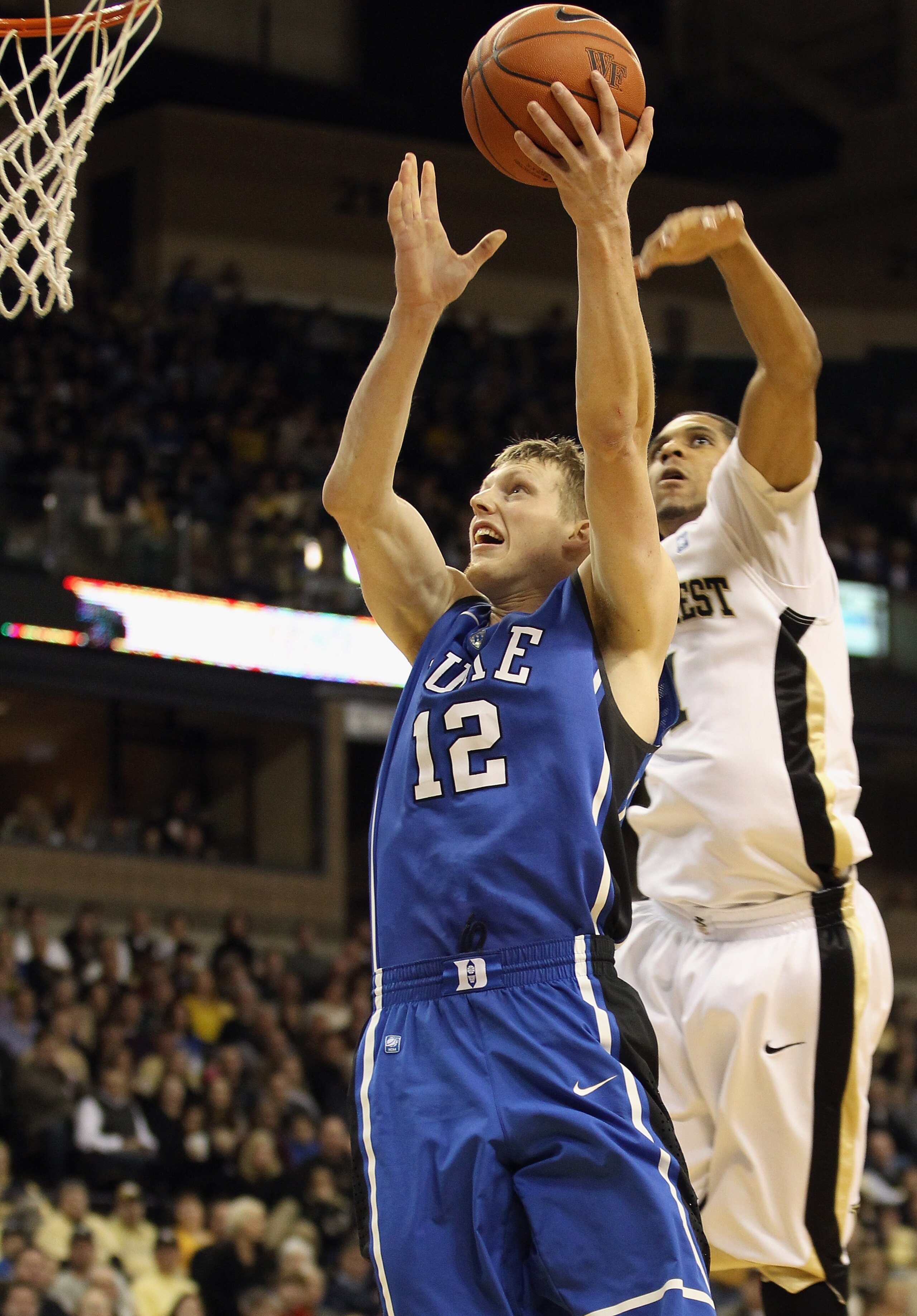 WINSTON SALEM, NC - JANUARY 22:  Kyle Singler #12 of the Duke Blue Devils drives to the basket against Ty Walker #40 of the Wake Forest Demon Deacons at Lawrence Joel Coliseum on January 22, 2011 in Winston Salem, North Carolina.  (Photo by Streeter Lecka