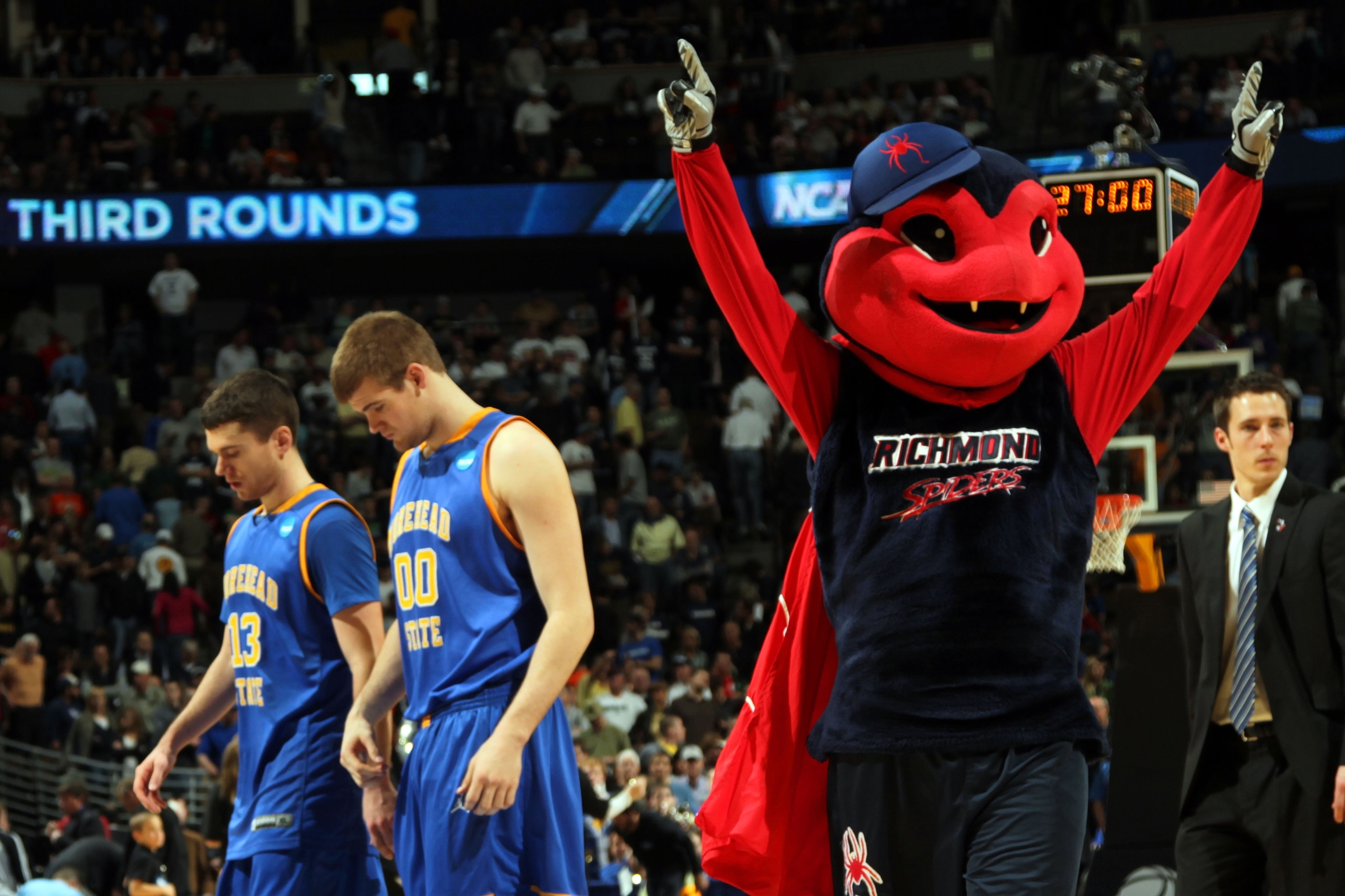 DENVER, CO - MARCH 19:  The Richmond Spiders mascot celebrates after the game as Ty Proffitt #13 and Drew Kelly #00 of the Morehead State Eagles walk off the court during the third round of the 2011 NCAA men's basketball tournament at Pepsi Center on Marc