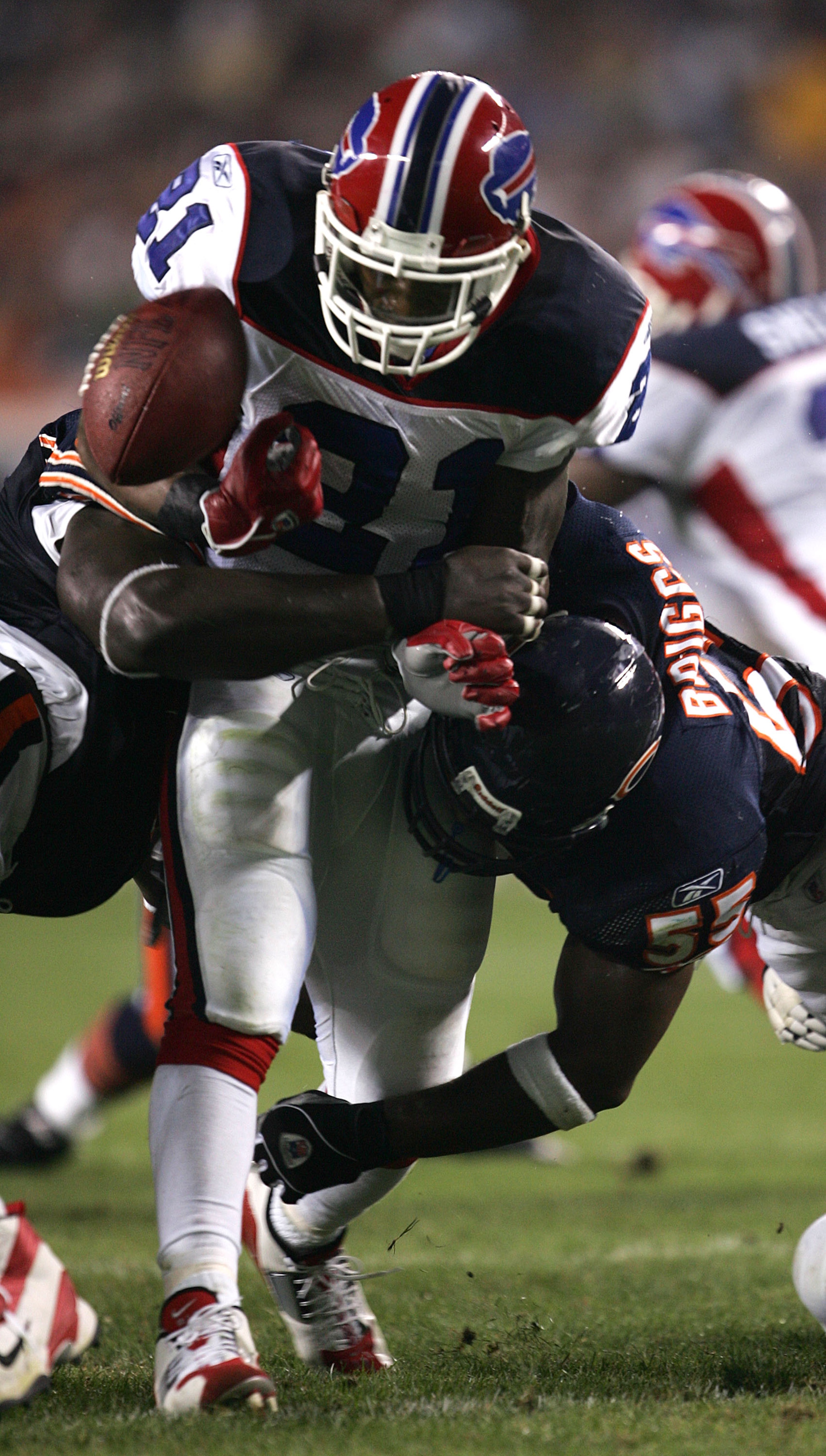 CHICAGO - AUGUST 26:  Running back Willis McGahee #21 of the Buffalo Bills fumbles the ball after being hit by linebacker Lance Briggs #55 (R) and tackle Tommie Harris #91 of the Chicago Bears on August 26, 2005 at Soldier Field in Chicago, Illinois.  (Ph