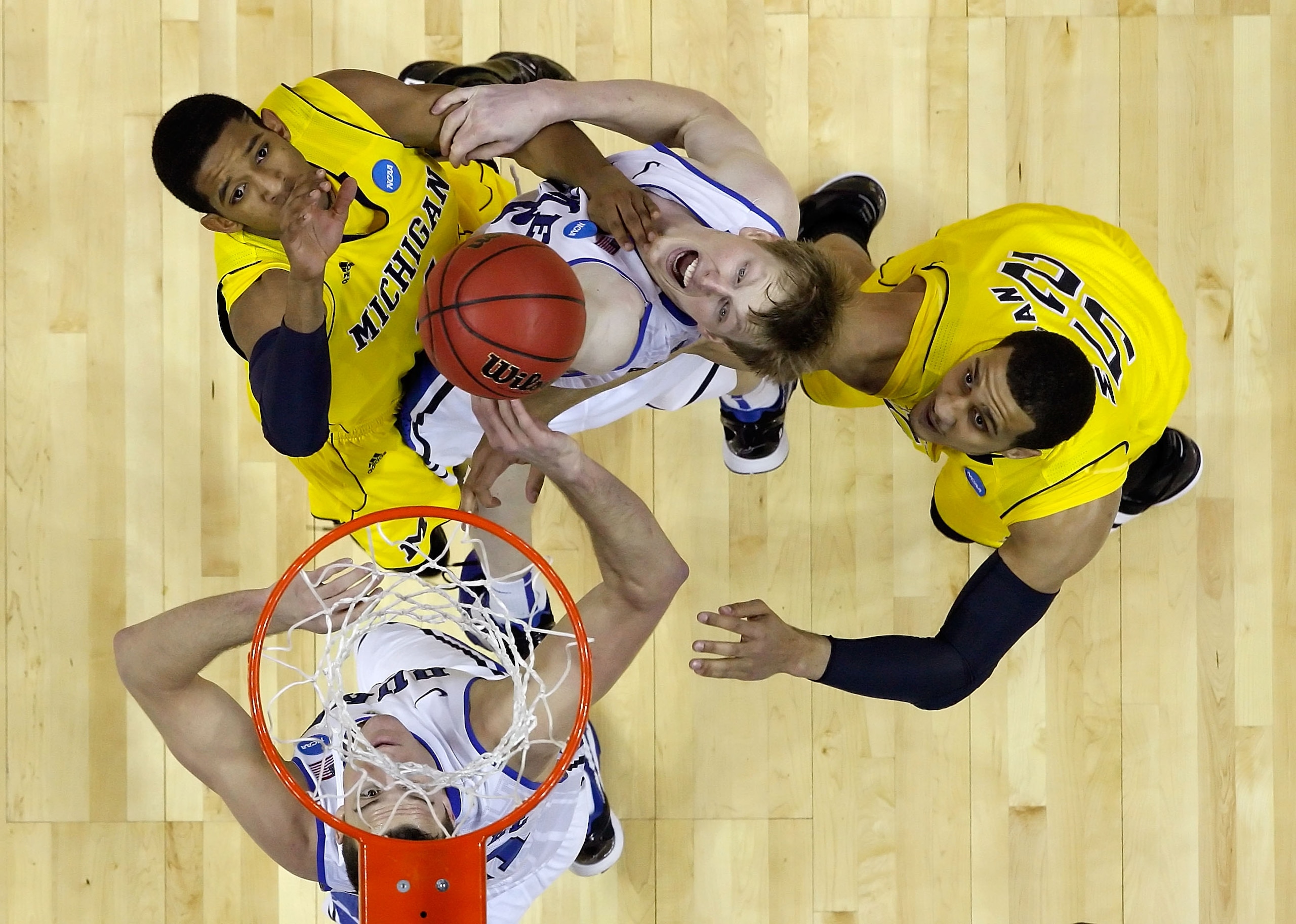 CHARLOTTE, NC - MARCH 20:  Darius Morris #4 of the Michigan Wolverines and Kyle Singler #12 of the Duke Blue Devils go up for a rebound alongisde Jordan Morgan #52 of the Michigan Wolverines during the third round of the 2011 NCAA men's basketball tournam