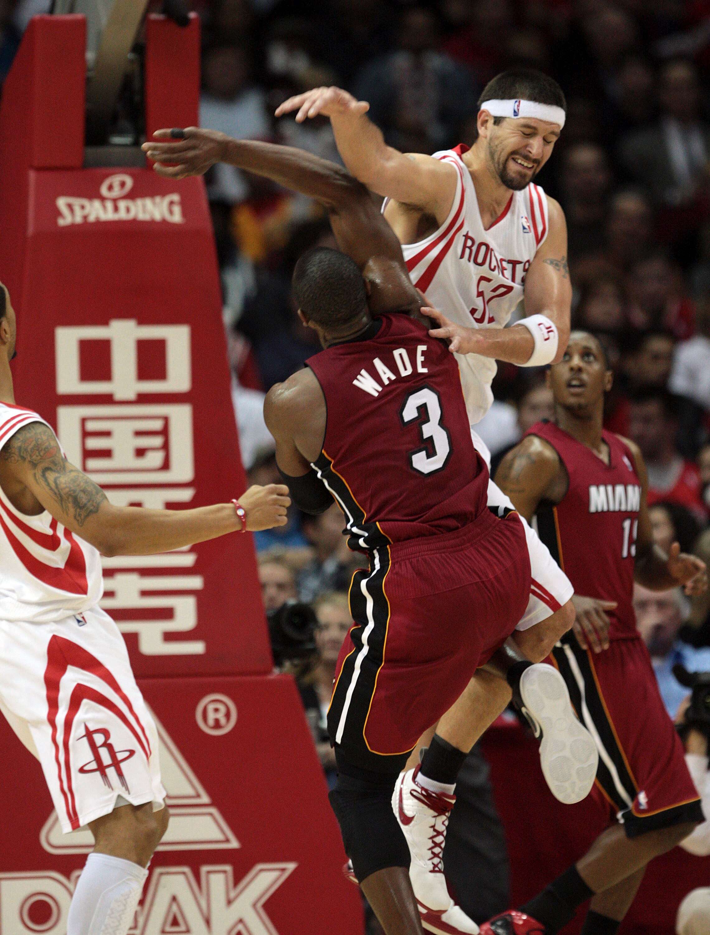 HOUSTON - DECEMBER 29: Dwyane Wade #3 of the Miami Heat takes a hard hit from Brad Miller #52 of the Houston Rockets as he drives to the basket in the fourth quarter at Toyota Center on December 29, 2010 in Houston, Texas. Miami won 125-119.  NOTE TO USER