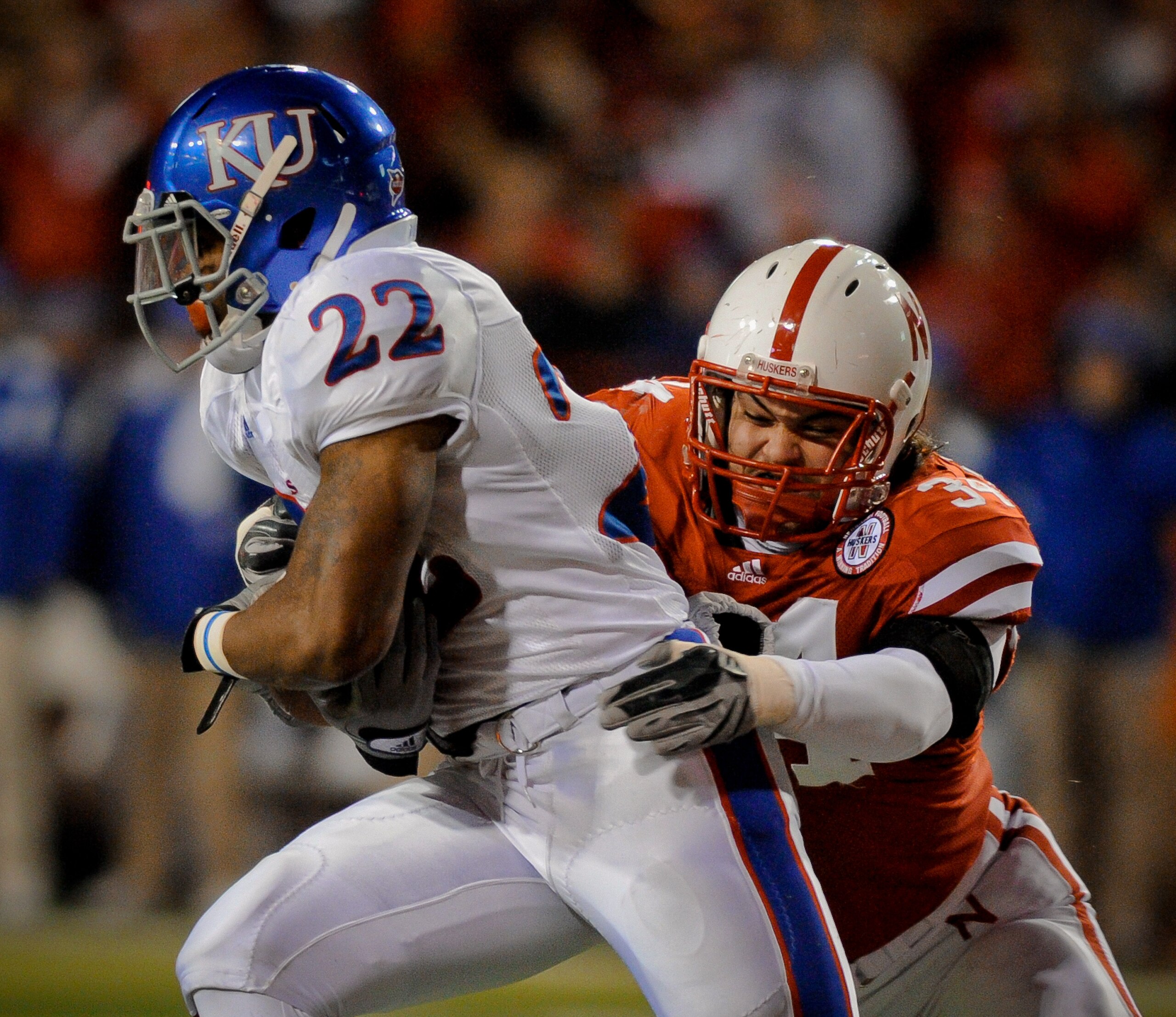 LINCOLN, NE - NOVEMBER 13: Cameron Meredith #34 of the Nebraska Cornhuskers grabs Angus Quigley #22 of the Kansas Jayhawks during first half action of their game at Memorial Stadium on November 13, 2010 in Lincoln, Nebraska.  (Photo by Eric Francis/Getty