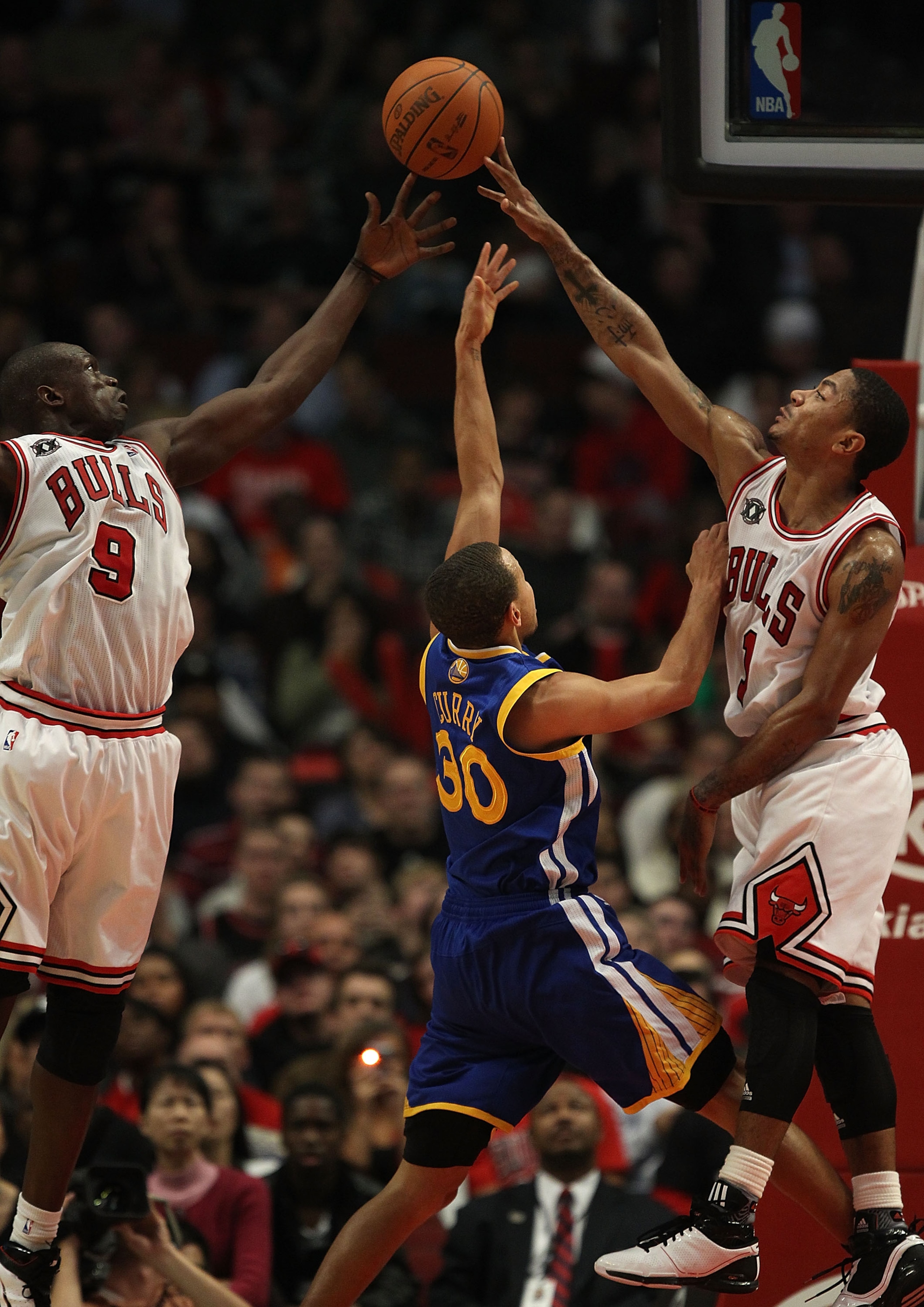 CHICAGO - NOVEMBER 11: Loul Deng #9 and Derrick Rose #1 of the Chicago Bulls block a shot by Stephen Curry #30 of the Golden State Warriors at the United Center on November 11, 2010 in Chicago, Illinois. The Bulls defeated the Warriors 120-90. NOTE TO USE