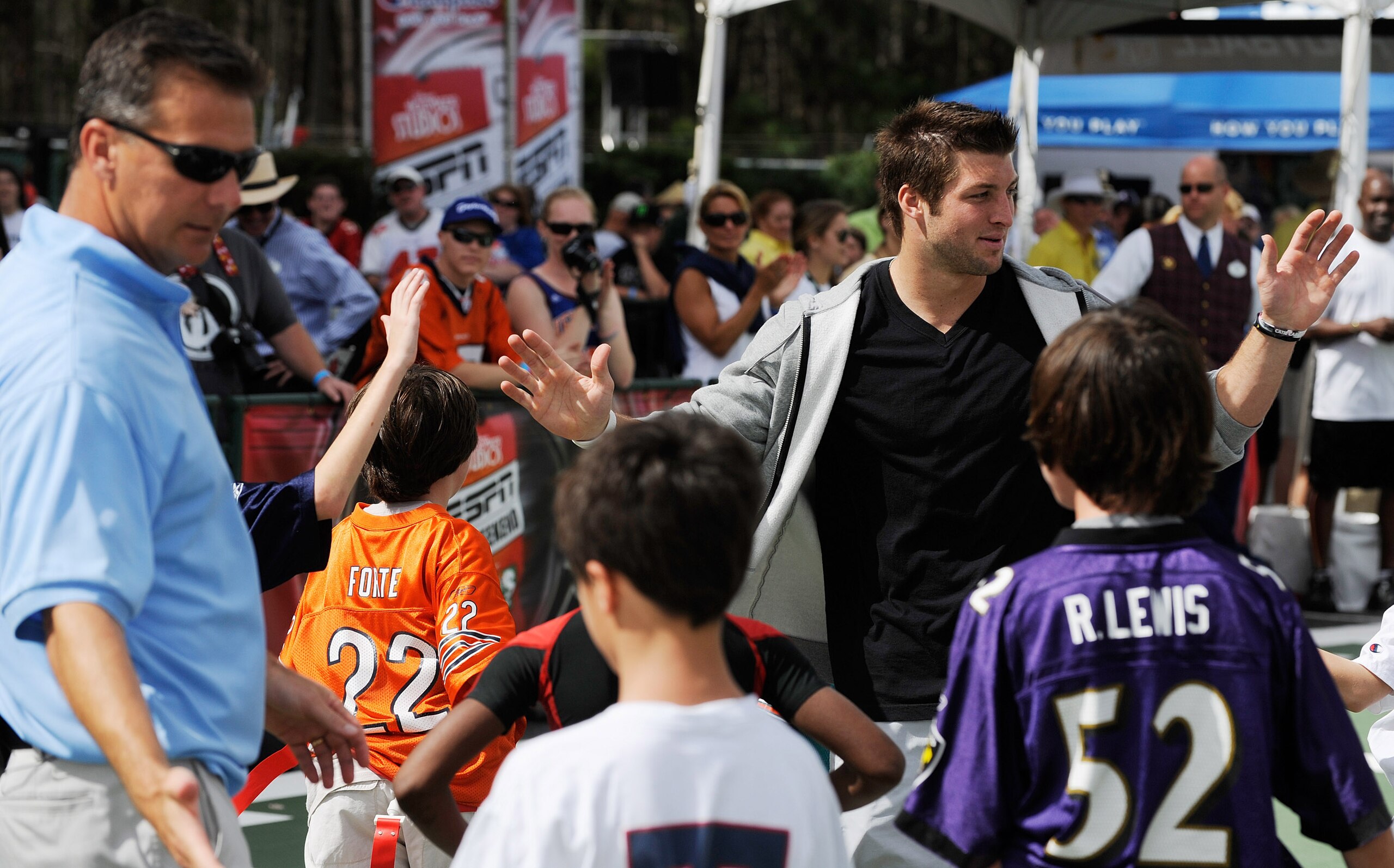 LAKE BUENA VISTA, FL - MARCH 05: In this handout photo provided by Disney Parks, Denver Broncos Quarterback Tim Tebow congratulates a group of young fans after a game of flag football at 'ESPN The Weekend' on March 05, 2011 at Disney's Hollywood Studios P