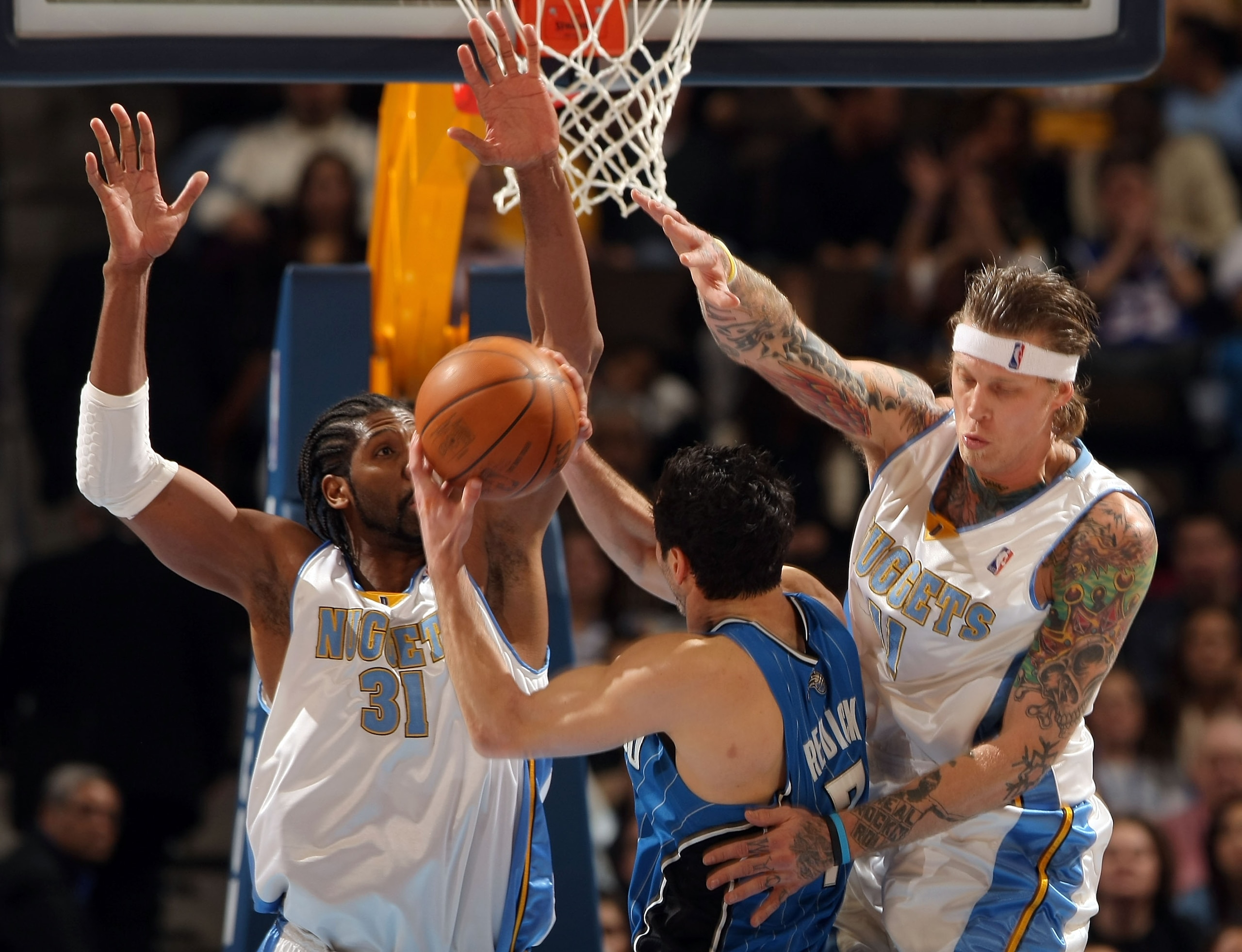 DENVER - JANUARY 13:  Chris Andersen #11 of the Denver Nuggets is called for a foul as he and Nene #31 defend against a shot by J.J. Redick #7 of the Orlando Magic during NBA action at Pepsi Center on January 13, 2010 in Denver, Colorado. The Nuggets defe