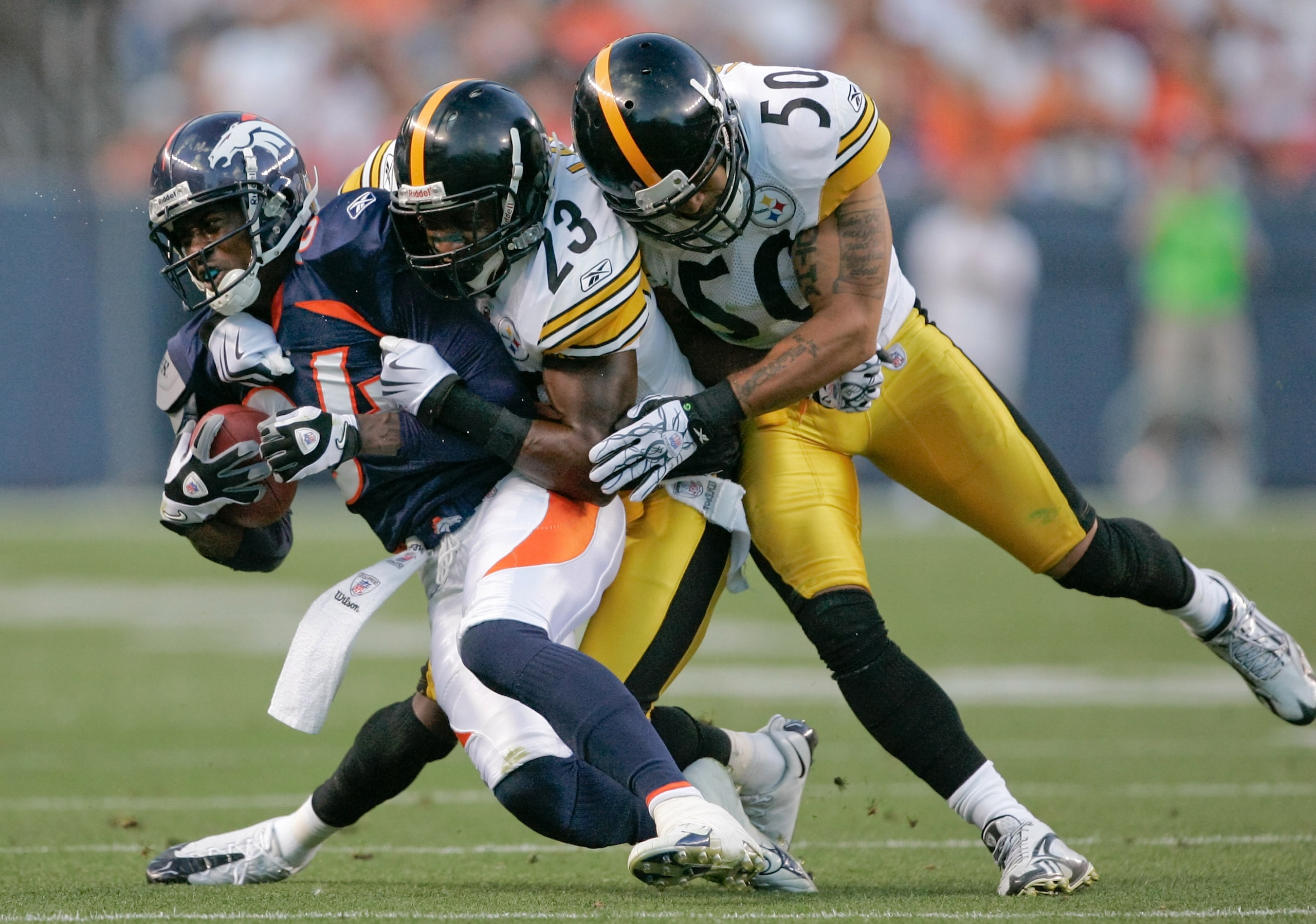 DENVER - AUGUST 29:  Wide receiver Brandon Lloyd #84 of the Denver Broncos is brought down by cornerback Keenan Lewis #23 and linebacker Larry Foote #50 of the Pittsburgh Steelers in the second quarter at INVESCO Field at Mile High on August 29, 2010 in D