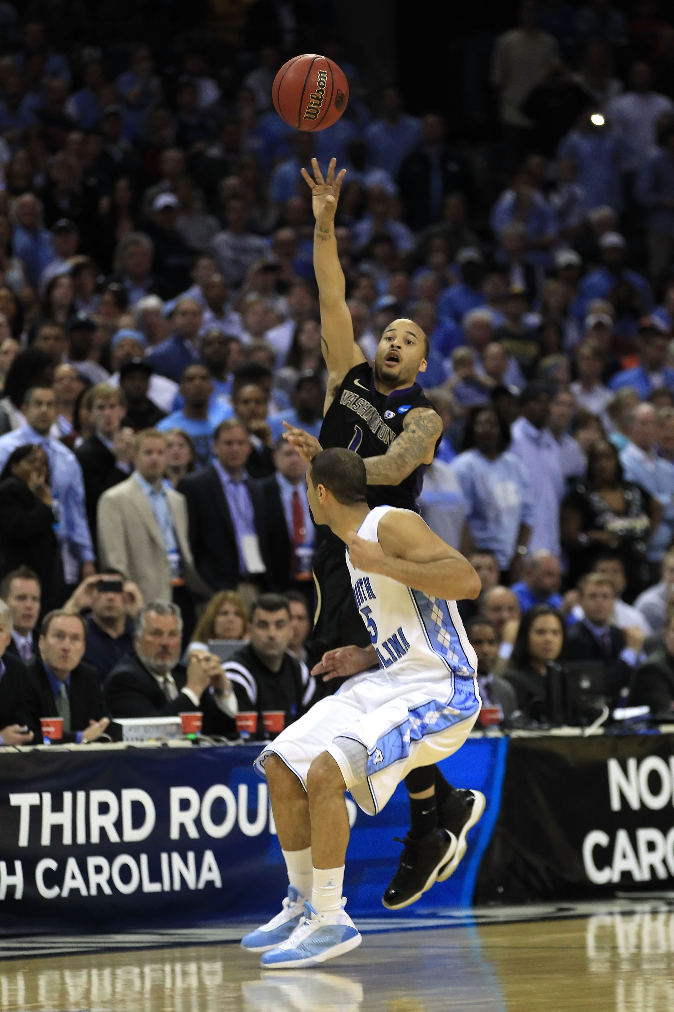 CHARLOTTE, NC - MARCH 20:  Venoy Overton #1 of the Washington Huskies throws up a shot from half court with under five seconds remaining in the game over Kendall Marshall #5 of the North Carolina Tar Heels during the third round of the 2011 NCAA men's bas