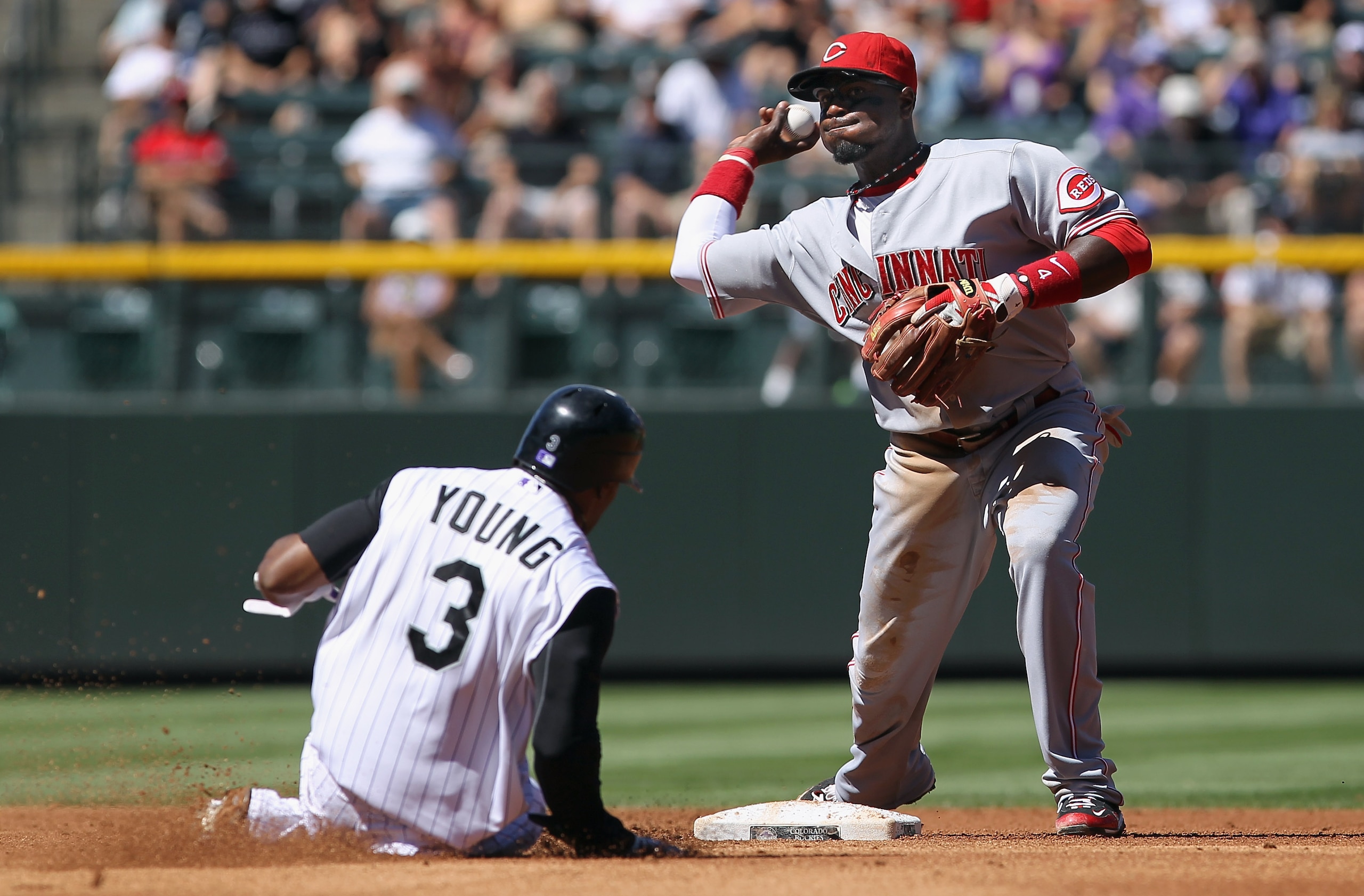 DENVER - SEPTEMBER 09:  Second baseman Brandon Phillips #4 of the Cincinnati Reds turns a double play on Eric Young Jr #3 of the Colorado Rockies on a grounder by Dexter Fowler in the first inning at Coors Field on September 9, 2010 in Denver, Colorado.