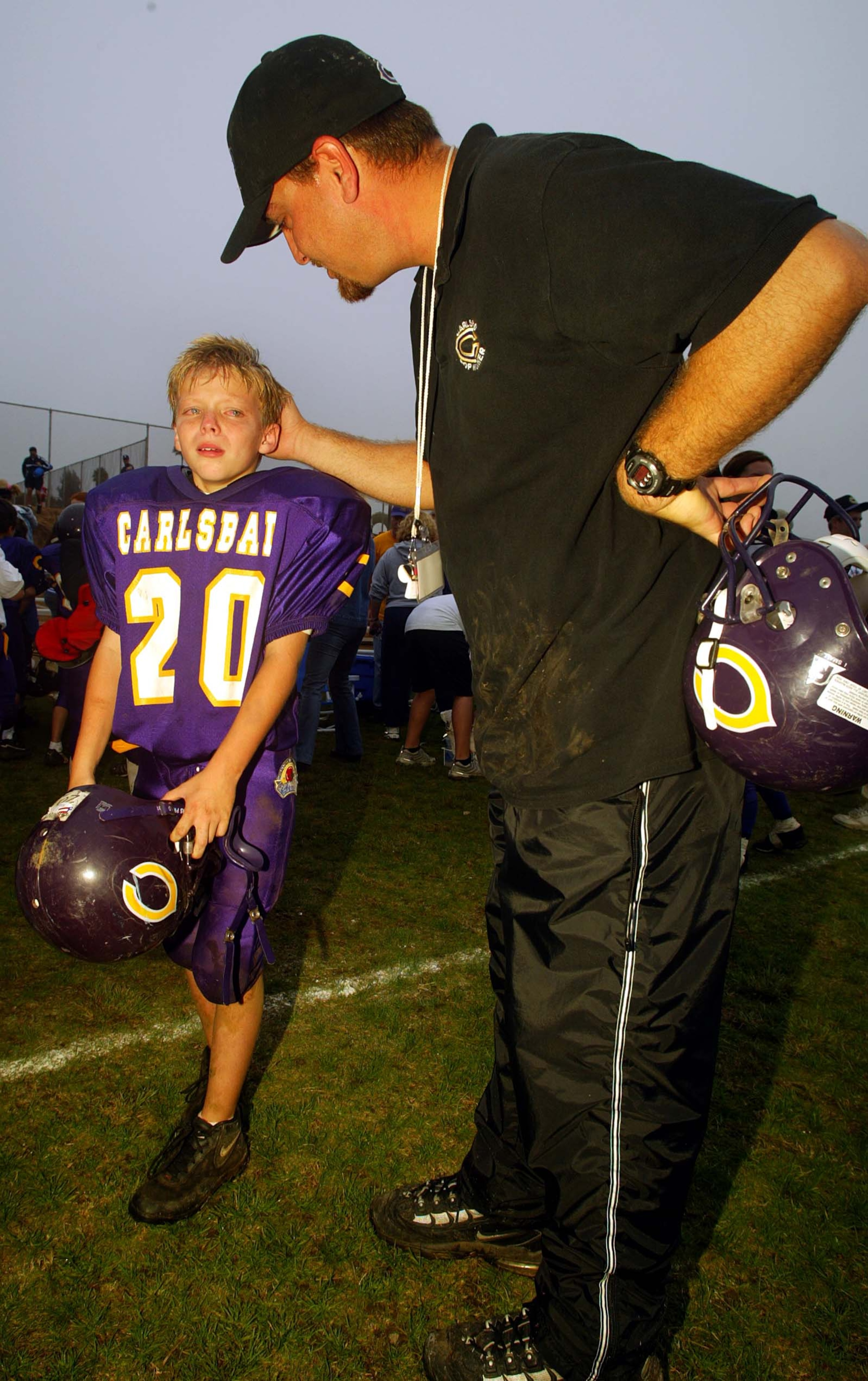 CARLSBAD, CA - NOVEMBER 9:  A coach of the Carlsbad Mighty Lancers (8&under) consoles one of his players after his team's loss to the Torrey Pines Falcons during the Pop Warner Division Finals on November 9, 2002 at Carlsbad High School, in Carlsbad, Cali