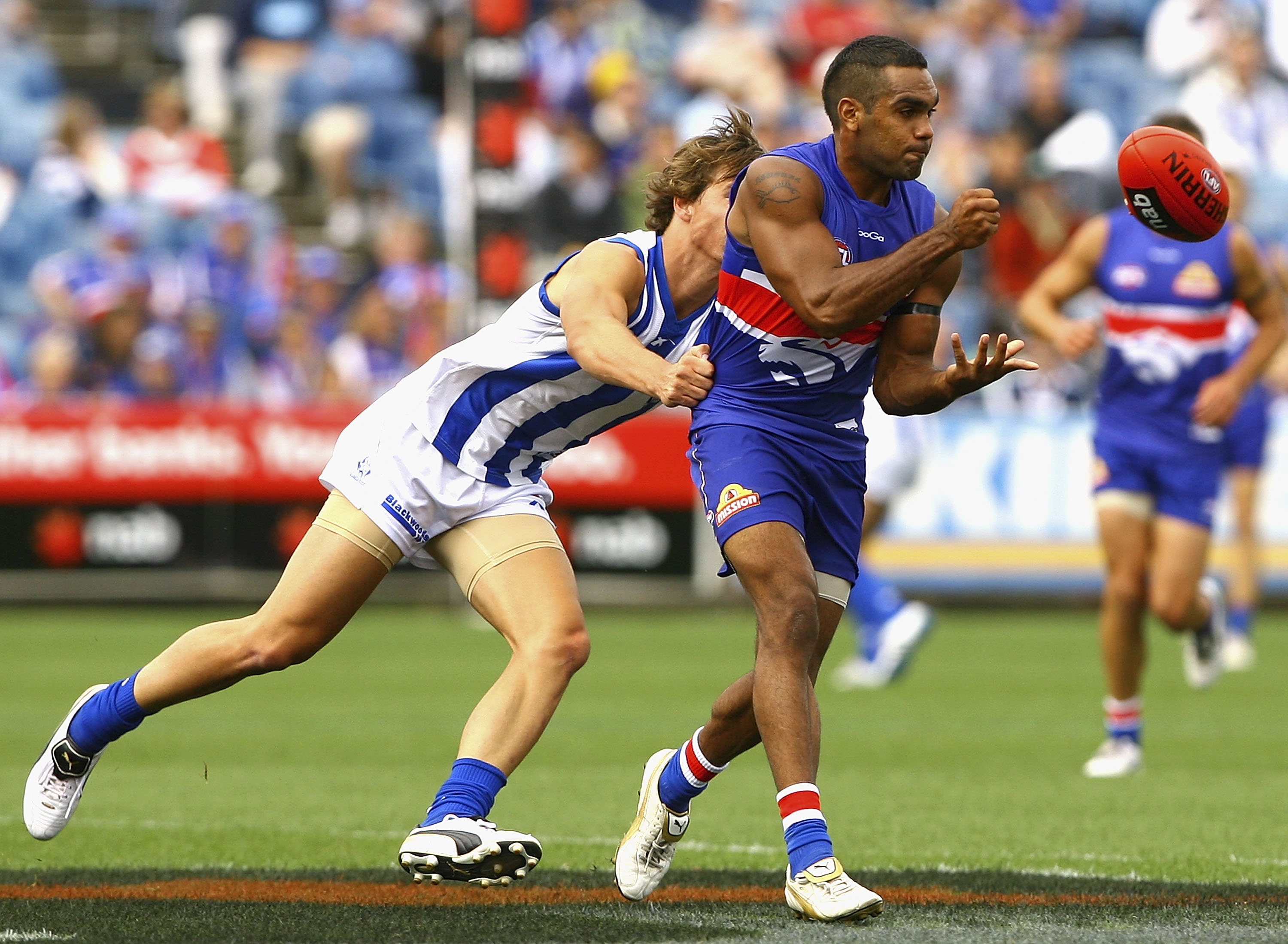 MELBOURNE, AUSTRALIA - FEBRUARY 20: Nathan Djerrkura of the Bulldogs handballs under pressure during the Pool Six NAB Cup round one AFL match between the North Melbourne Kangaroos and the Western Bulldogs at Skilled Stadium on February 20, 2011 in Melbou
