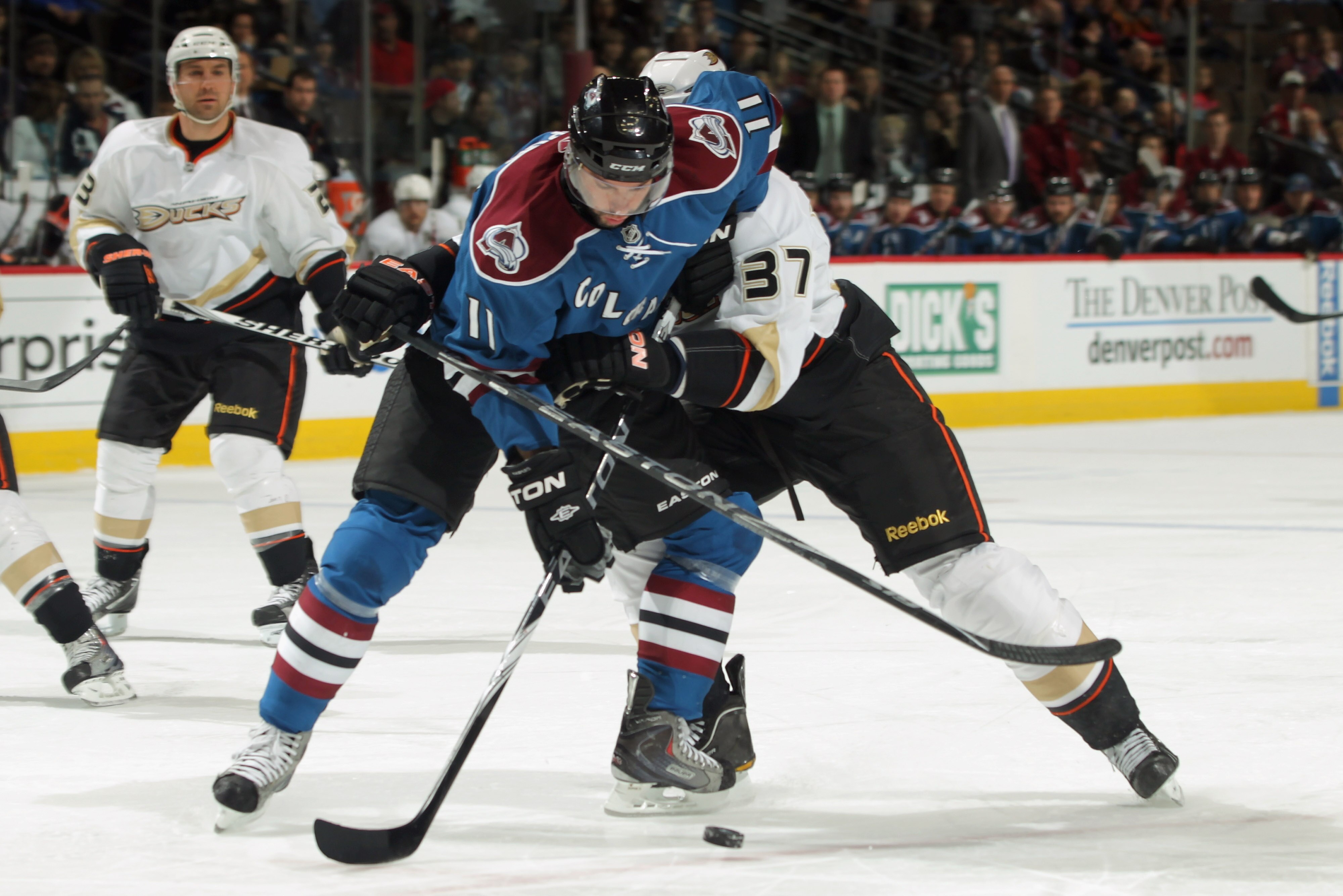 DENVER, CO - MARCH 11:  Philippe Dupuis #11 of the Colorado Avalanche tries to control the puck as Jarkko Ruutu #37 of the Anaheim Ducks receives a penalty for holding during NHL action at the Pepsi Center on March 11, 2011 in Denver, Colorado.  (Photo by