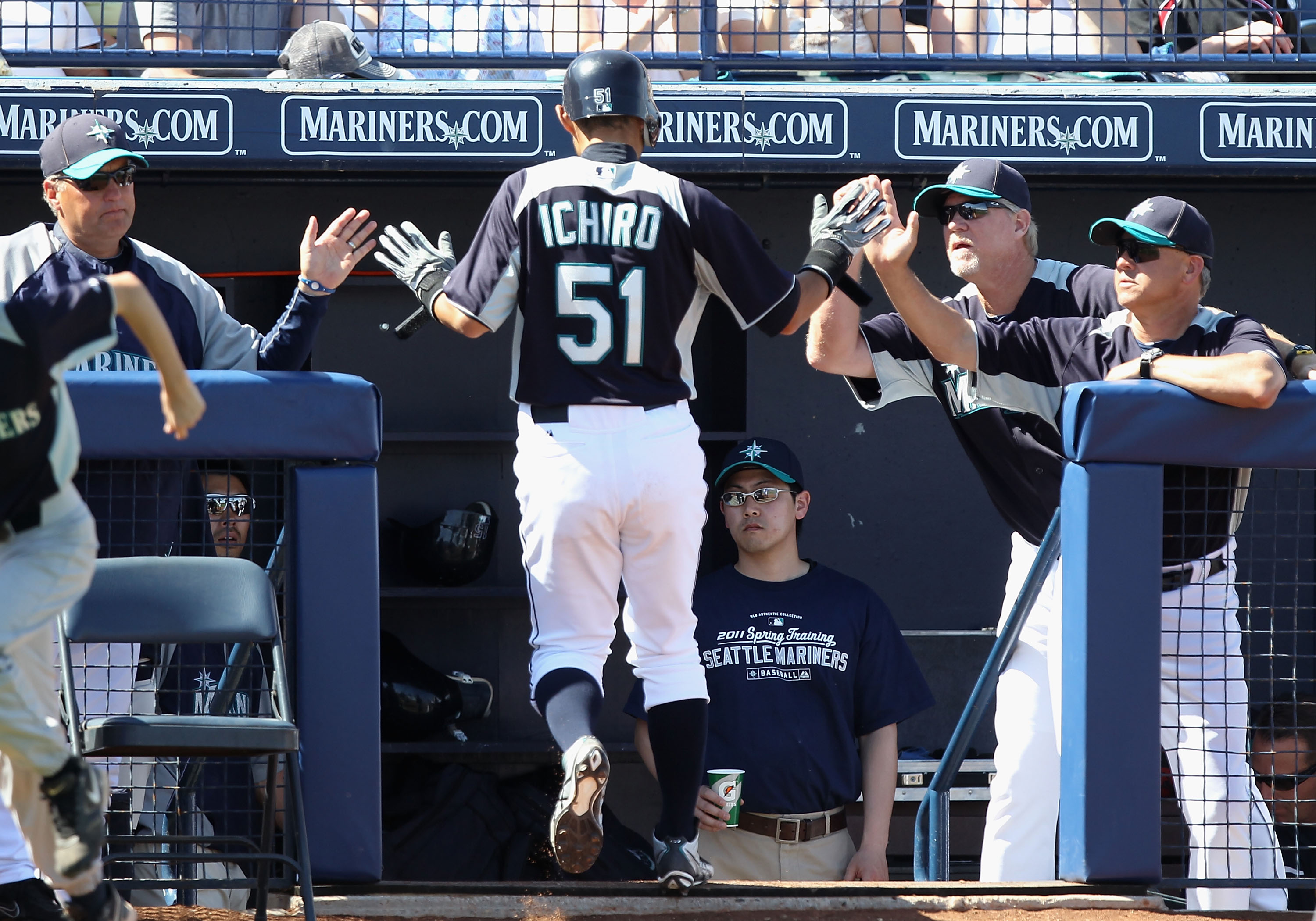 PEORIA, AZ - MARCH 12:  Ichiro Suzuki #51 of the Seattle Mariners high fives teammates after scoring a run against the Oakland Athletics during the second inning of the spring training game at Peoria Stadium on March 12, 2011 in Peoria, Arizona.  (Photo b