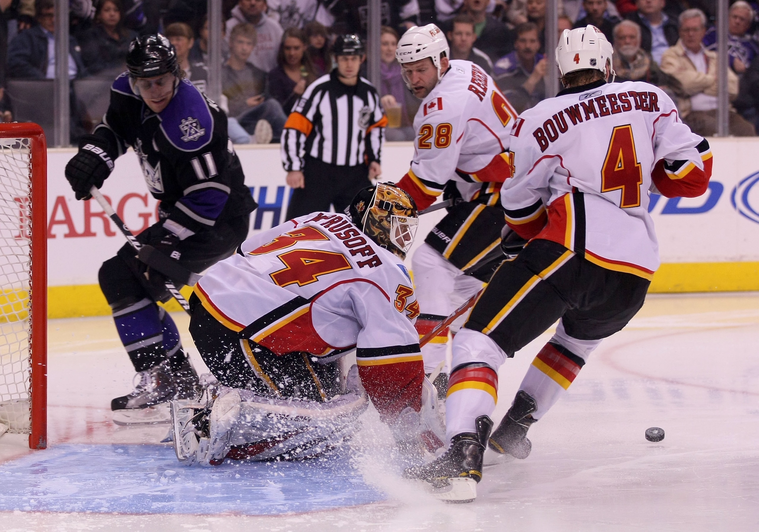 LOS ANGELES, CA - MARCH 21:  Goaltender Miikka Kiprusoff #34 of the Calgary Flames makes a pad save as teammate Jay Bouwmeester #4 of the Calgary Flames looks to clear the puck during their NHL game against the Los Angeles Kings at Staples Center on March