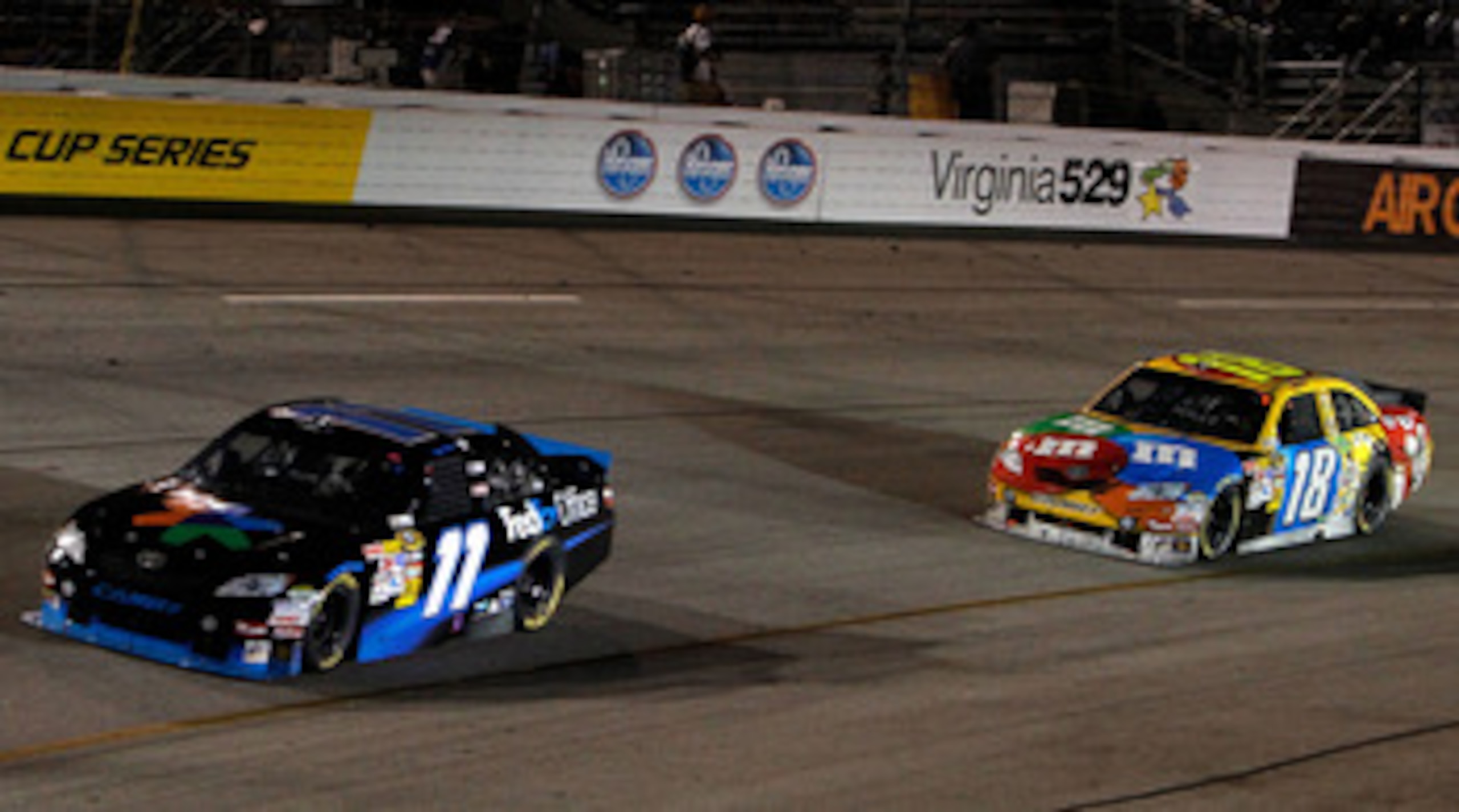 RICHMOND, VA - SEPTEMBER 11:  Denny Hamlin, driver of the #11 FedEx Office Toyota, leads Kyle Busch, driver of the #18 M&M's Toyota, during the NASCAR Sprint Cup Series Air Guard 400 at Richmond International Raceway on September 11, 2010 in Richmond, Vir