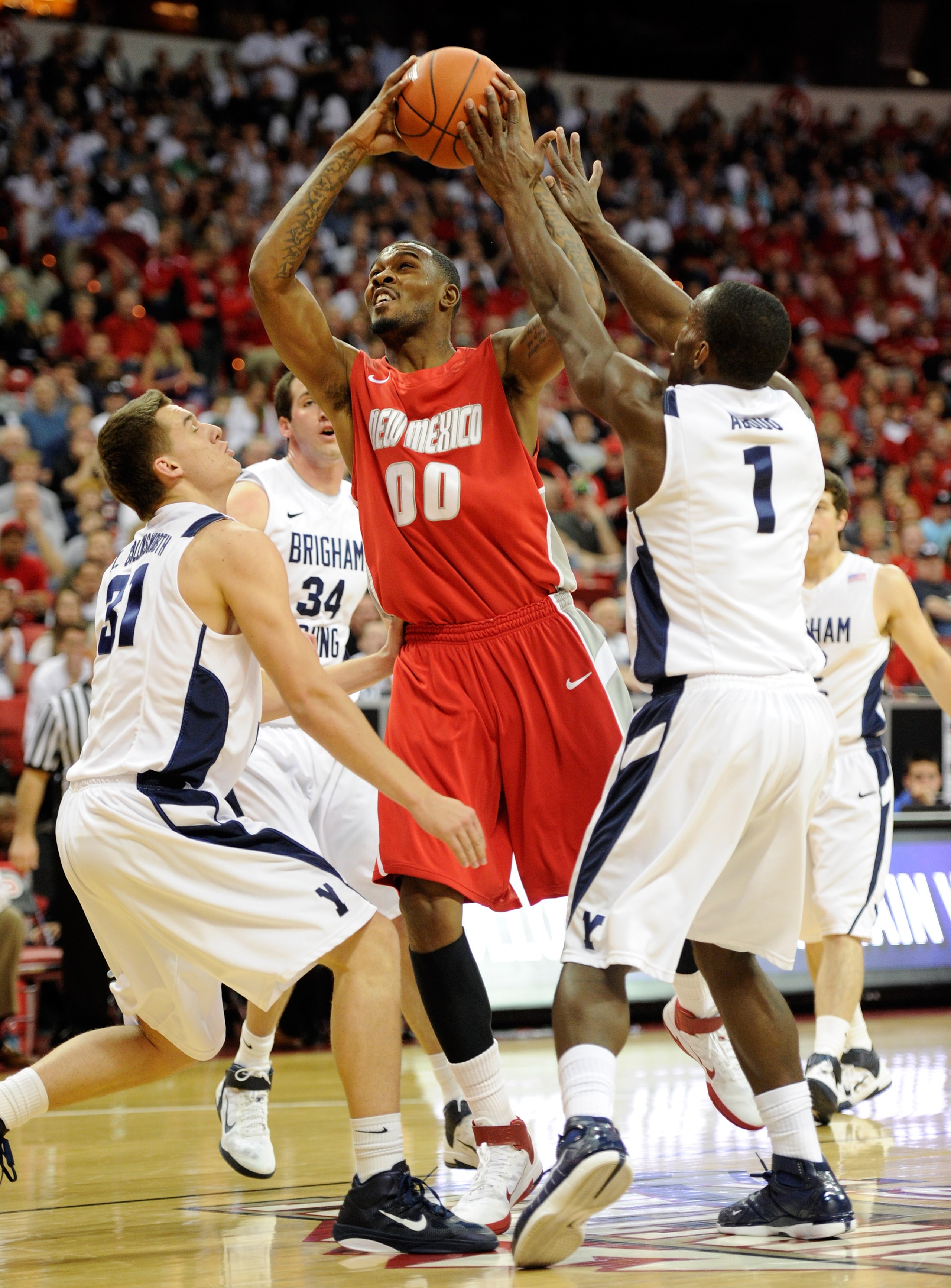 LAS VEGAS, NV - MARCH 11: A.J. Hardeman #00 of the New Mexico Lobos is fouled by Charles Abouo #1 # of the Brigham Young University Cougars as BYU's Kyle Collinworth defends during a semifinal game of the Conoco Mountain West Conference Basketball tourna LAS VEGAS, NV - MARCH 11: A.J. Hardeman #00 of the New Mexico Lobos is fouled by Charles Abouo #1 # of the Brigham Young University Cougars as BYU's Kyle Collinworth defends during a semifinal game of the Conoco Mountain West Conference Basketball tourna