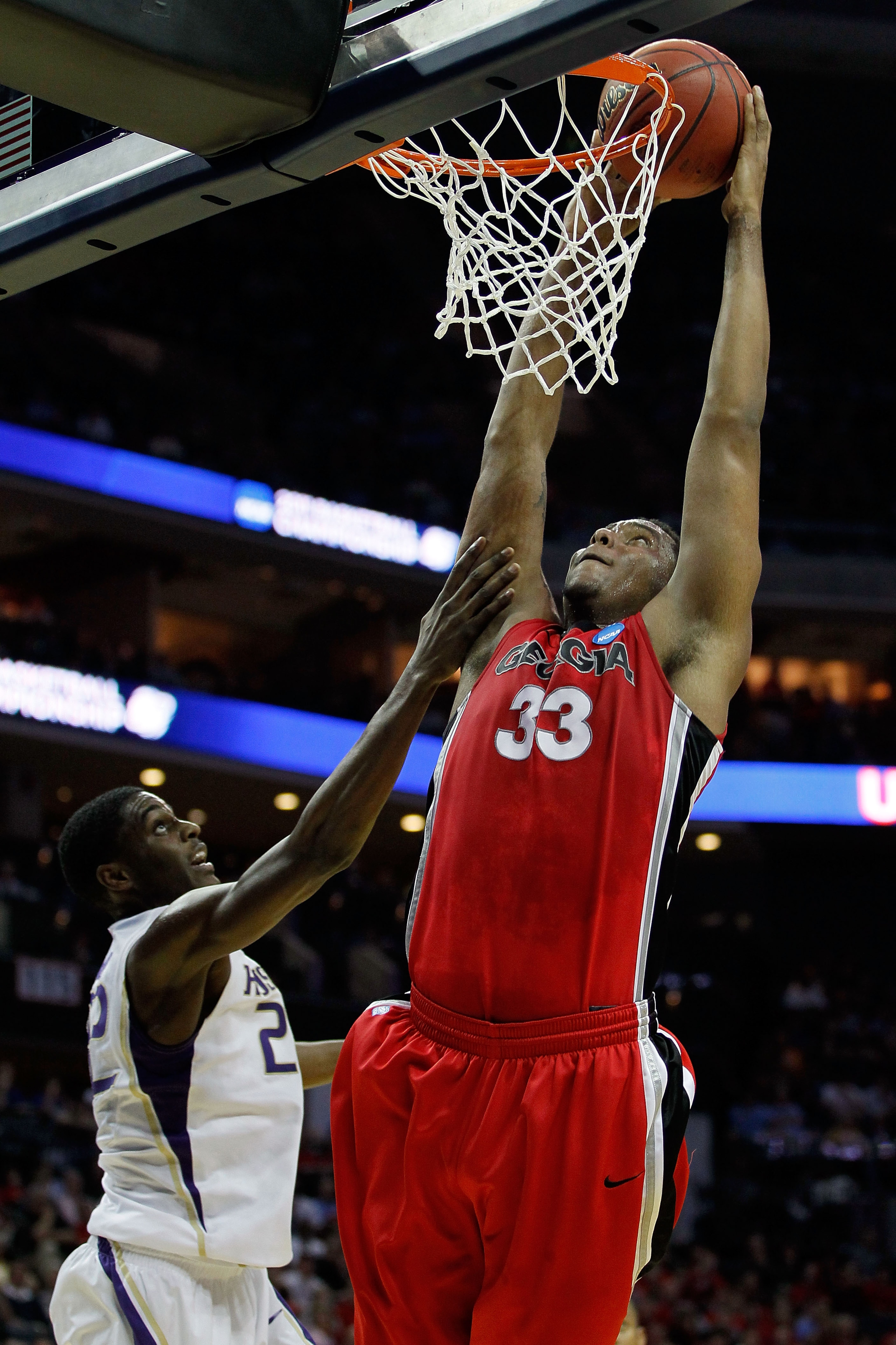 CHARLOTTE, NC - MARCH 18:  Trey Thompkins #33 of the Georgia Bulldogs goes up for a dunk over Justin Holiday #22 of the Washington Huskies in the first half during the second round of the 2011 NCAA men's basketball tournament at Time Warner Cable Arena on