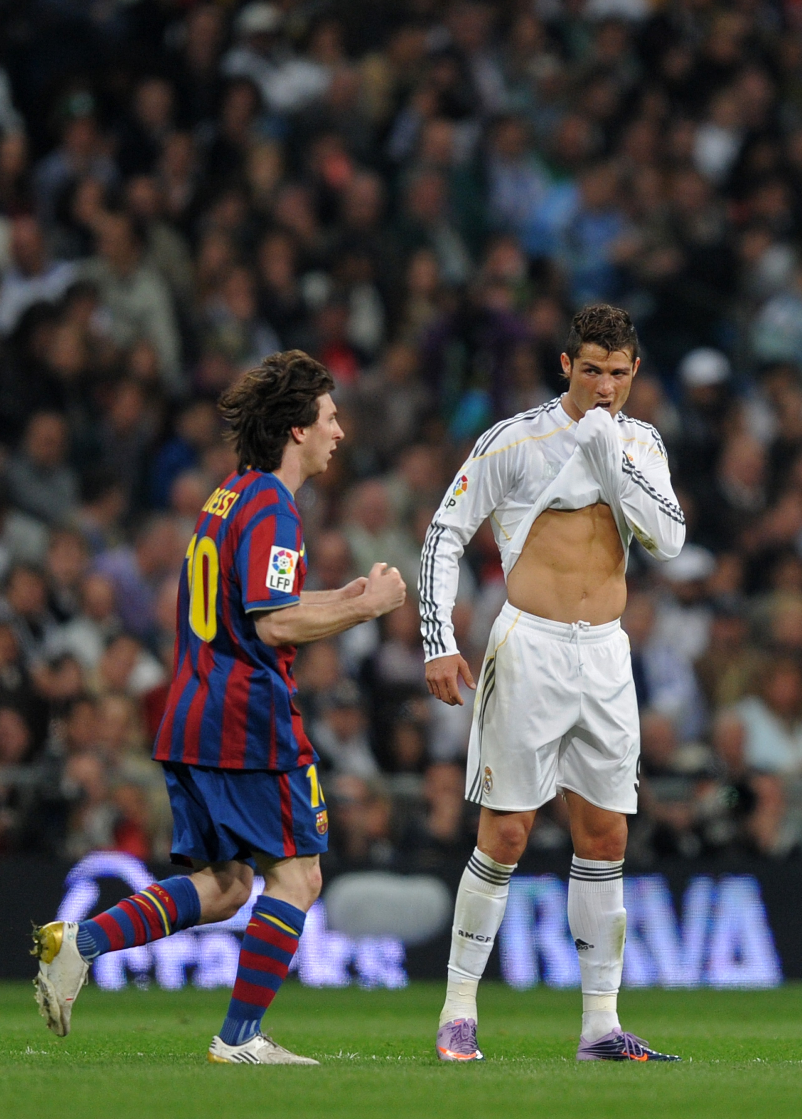 MADRID, SPAIN - APRIL 10:  Lionel Messi (L) of FC Barcelona clenches his fists celebrating scoring his sides opening goal as Cristiano Ronaldo of Real Madrid reacts during the La Liga match between Real Madrid and Barcelona at the Estadio Santiago Bernabe