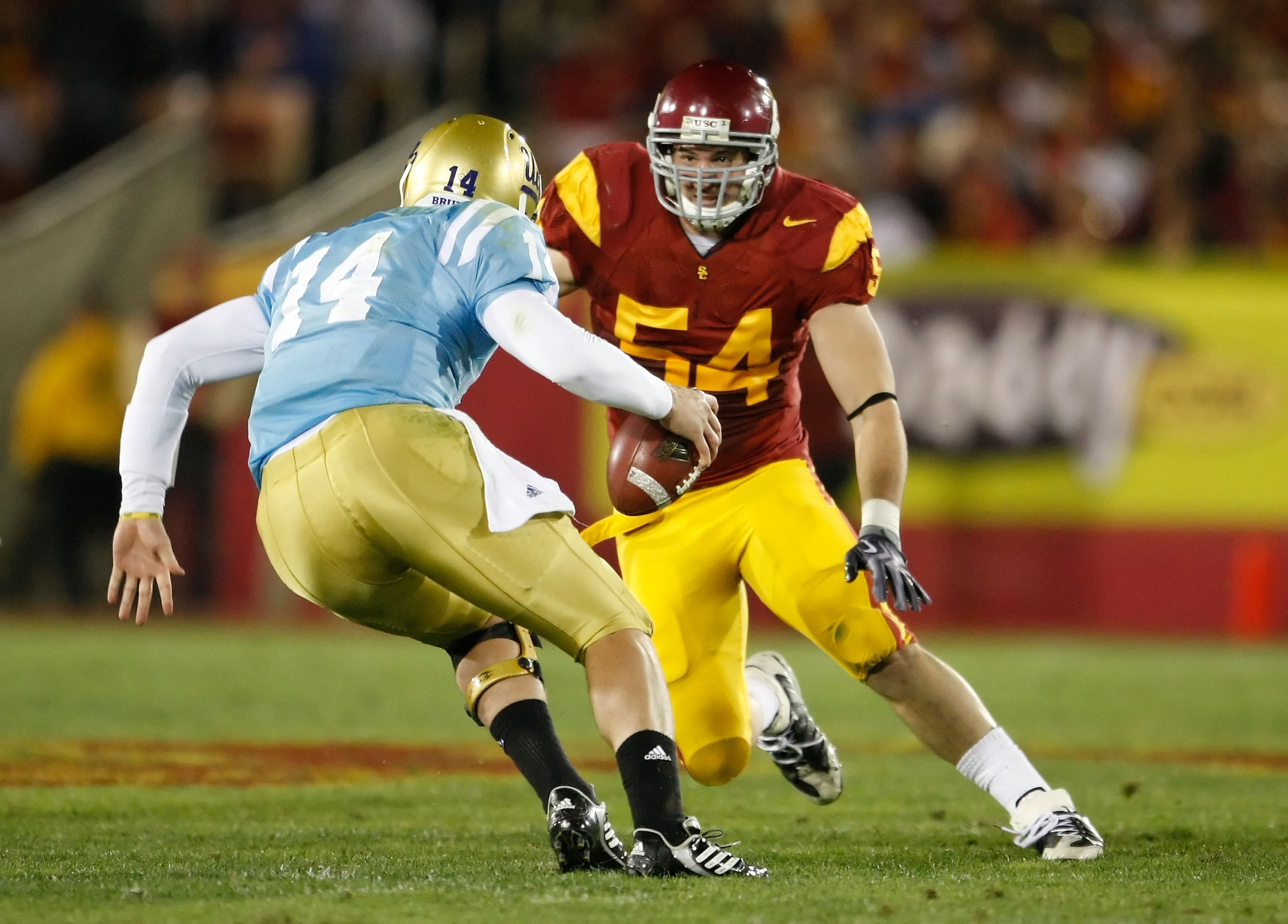 LOS ANGELES, CA - NOVEMBER 28:  Quarterback Kevin Prince #14 of the UCLA Bruins is pursued by Chris Galippo #54 of the USC Trojans in the first half at the Los Angeles Memorial Coliseum on November 28, 2009 in Los Angeles, California. USC defeated UCLA 28