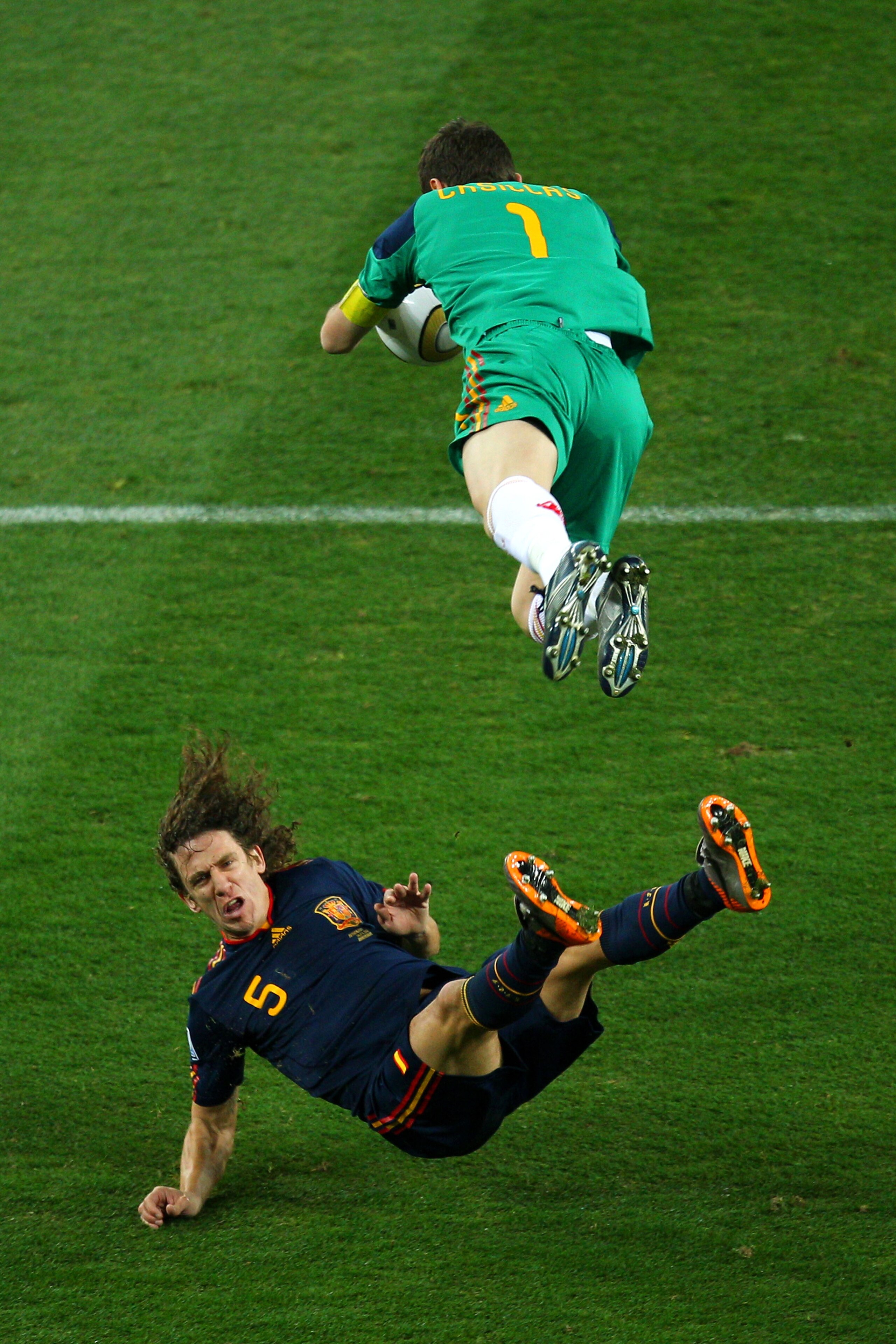 JOHANNESBURG, SOUTH AFRICA - JULY 11:  Iker Casillas of Spain catches the ball and falls over team mate Carles Puyol during the 2010 FIFA World Cup South Africa Final match between Netherlands and Spain at Soccer City Stadium on July 11, 2010 in Johannesb