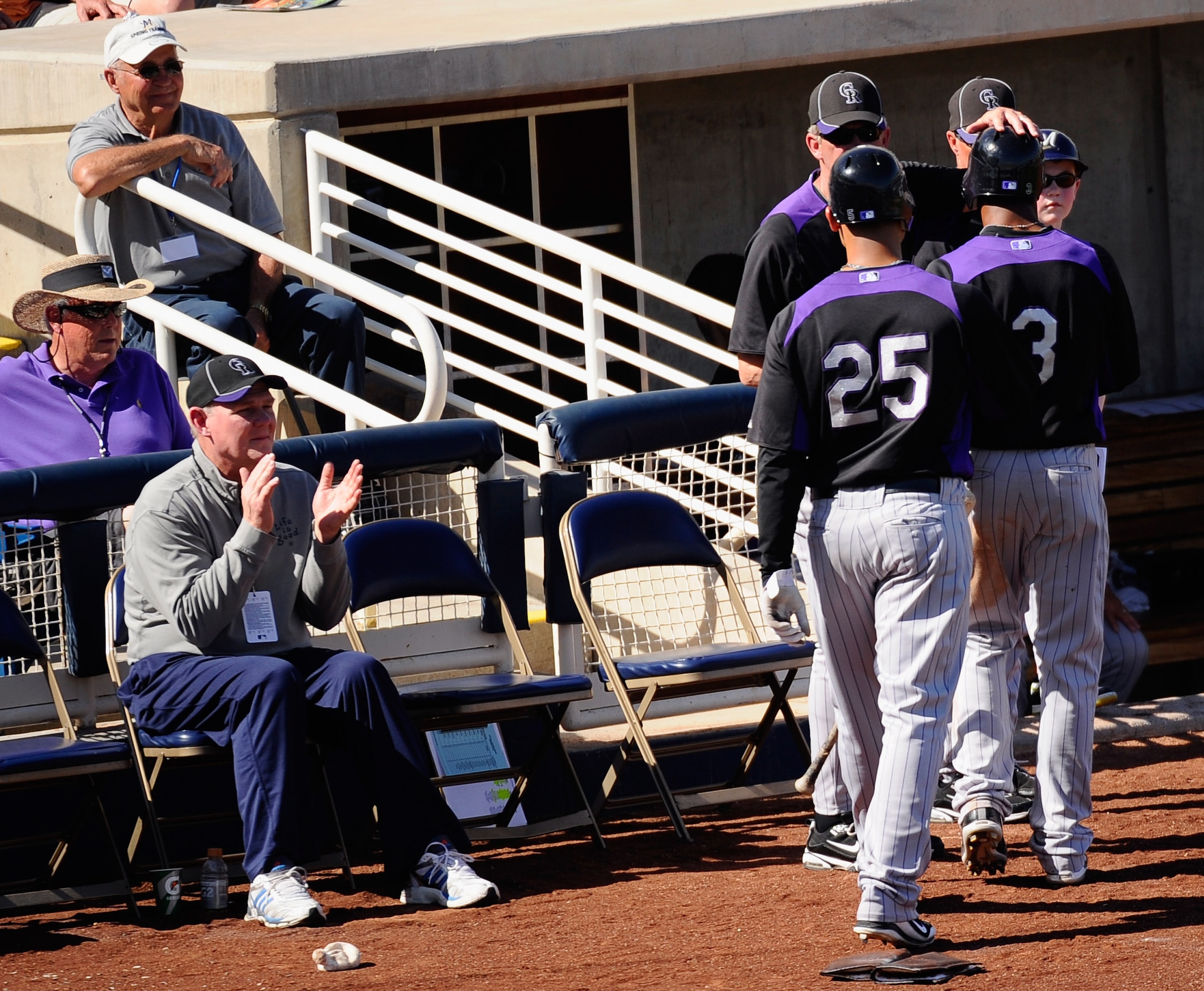 PHOENIX, AZ - MARCH 10:  George Karl (L) coach of the Denver Nuggets looks on as managerJim Tracy of the Colorado Rockies congratulates Carlos Gonzalez #25 and and Willy Taveras #3 after they scored on teammate Todd Helton's two-run double against the Mil