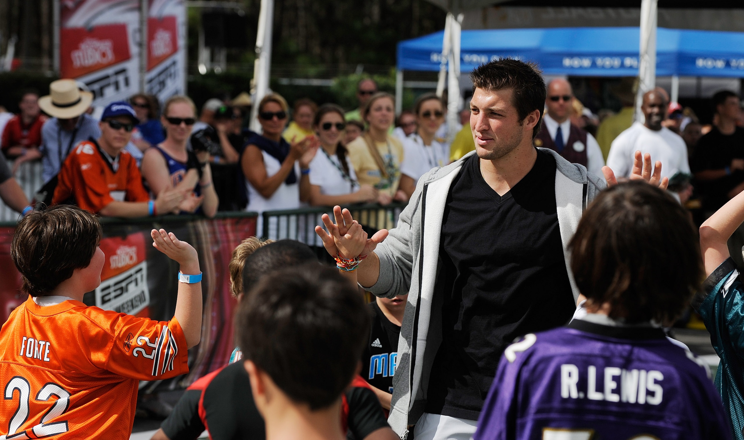 LAKE BUENA VISTA, FL - MARCH 05: In this handout photo provided by Disney Parks, Denver Broncos Quarterback Tim Tebow congratulates a group of young fans after a game of flag football at 'ESPN The Weekend' on March 05, 2011 at Disney's Hollywood Studios P