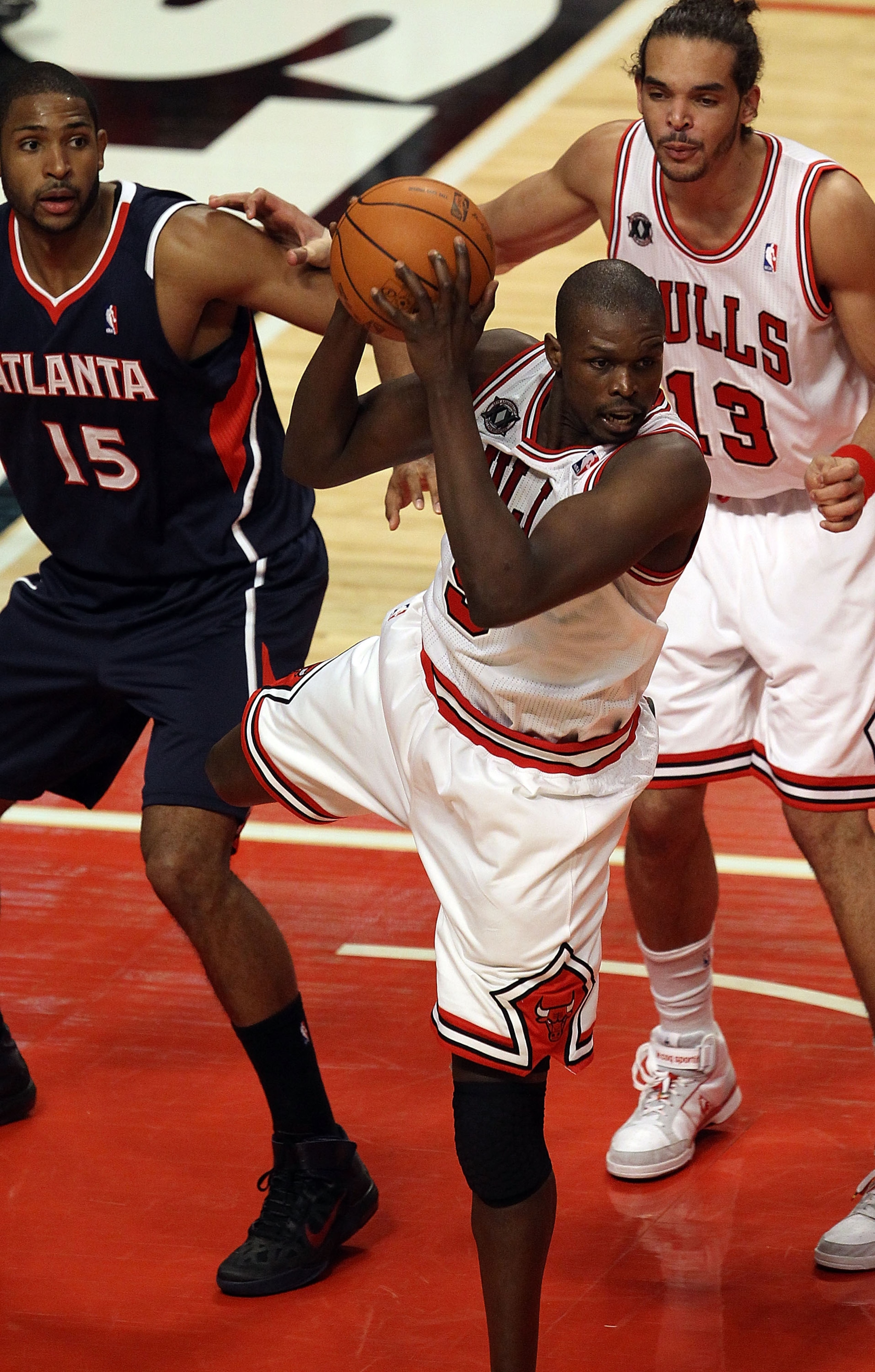 CHICAGO, IL - MARCH 11: Loul Deng #9 of the Chicago Bulls grabs a rebound in front of teammate Joakim Noah #13 and Al Horford #15 of the Atlanta Hawks at the United Center on March 11, 2011 in Chicago, Illinois. The Bulls defeated the Hawks 94-76. NOTE TO