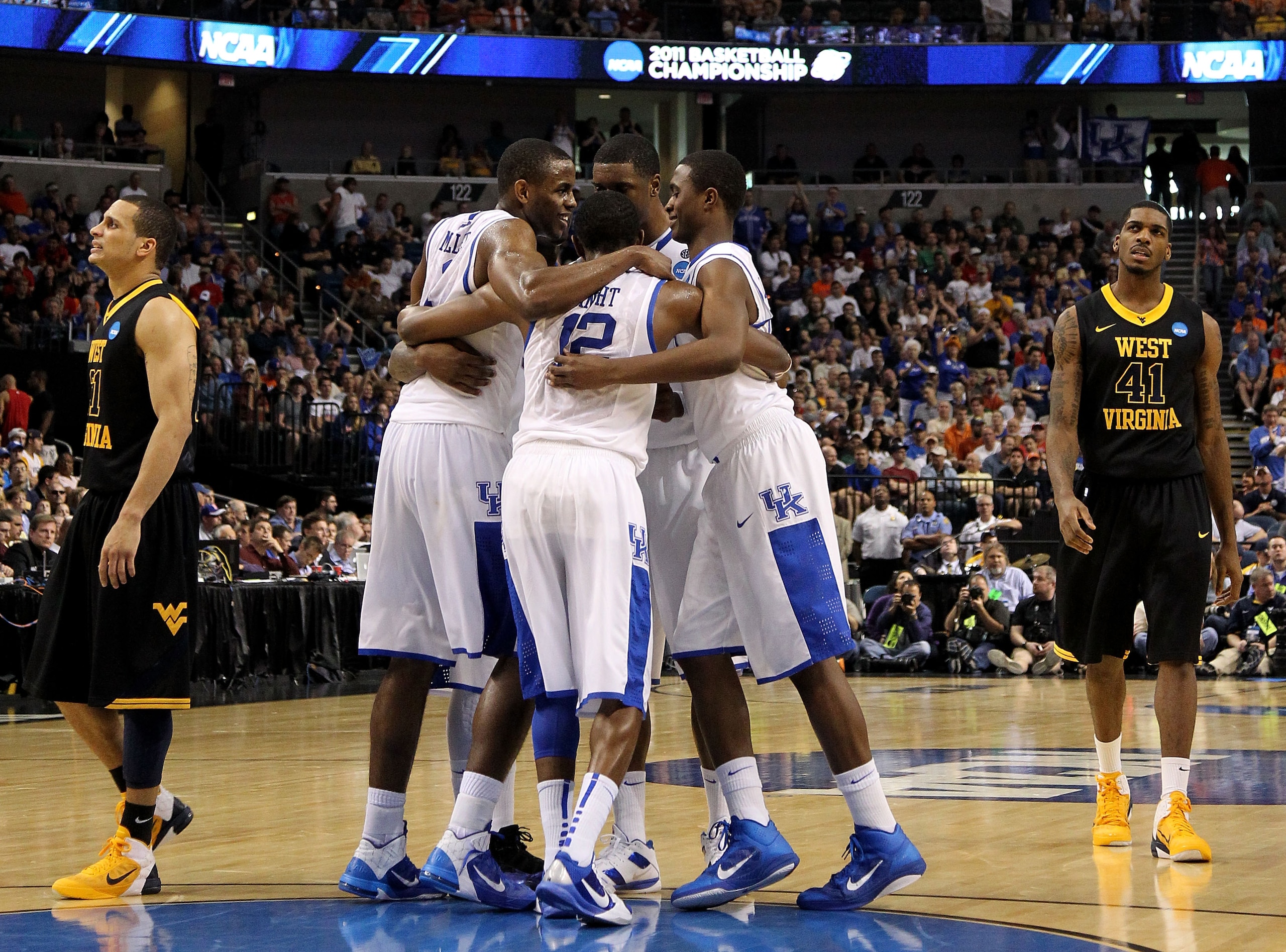 TAMPA, FL - MARCH 19:  Brandon Knight #12 of the Kentucky Wildcats huddles up with his teammates against as Joe Mazzulla #21 and John Flowers #41 of the West Virginia Mountaineers look on during the third round of the 2011 NCAA men's basketball tournament