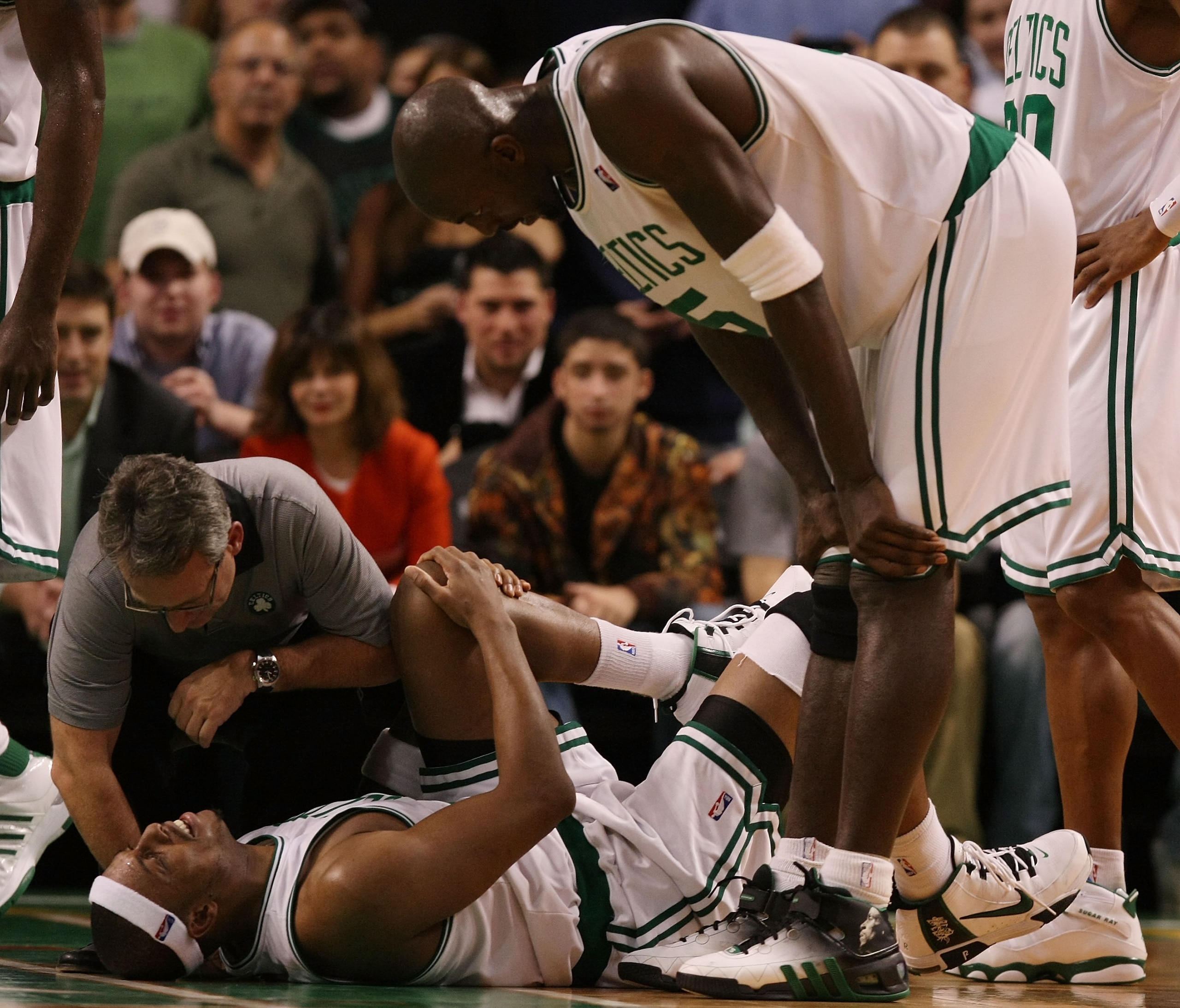 BOSTON - DECEMBER 15:  Paul Pierce #34 of the Boston Celtics is looked after by Ed Lecerte and teammate Kevin Garnett #5 after Pierce injured his knee late in the fourth quarter against the Utah Jazz on December 15, 2008 at TD Banknorth Garden in Boston,