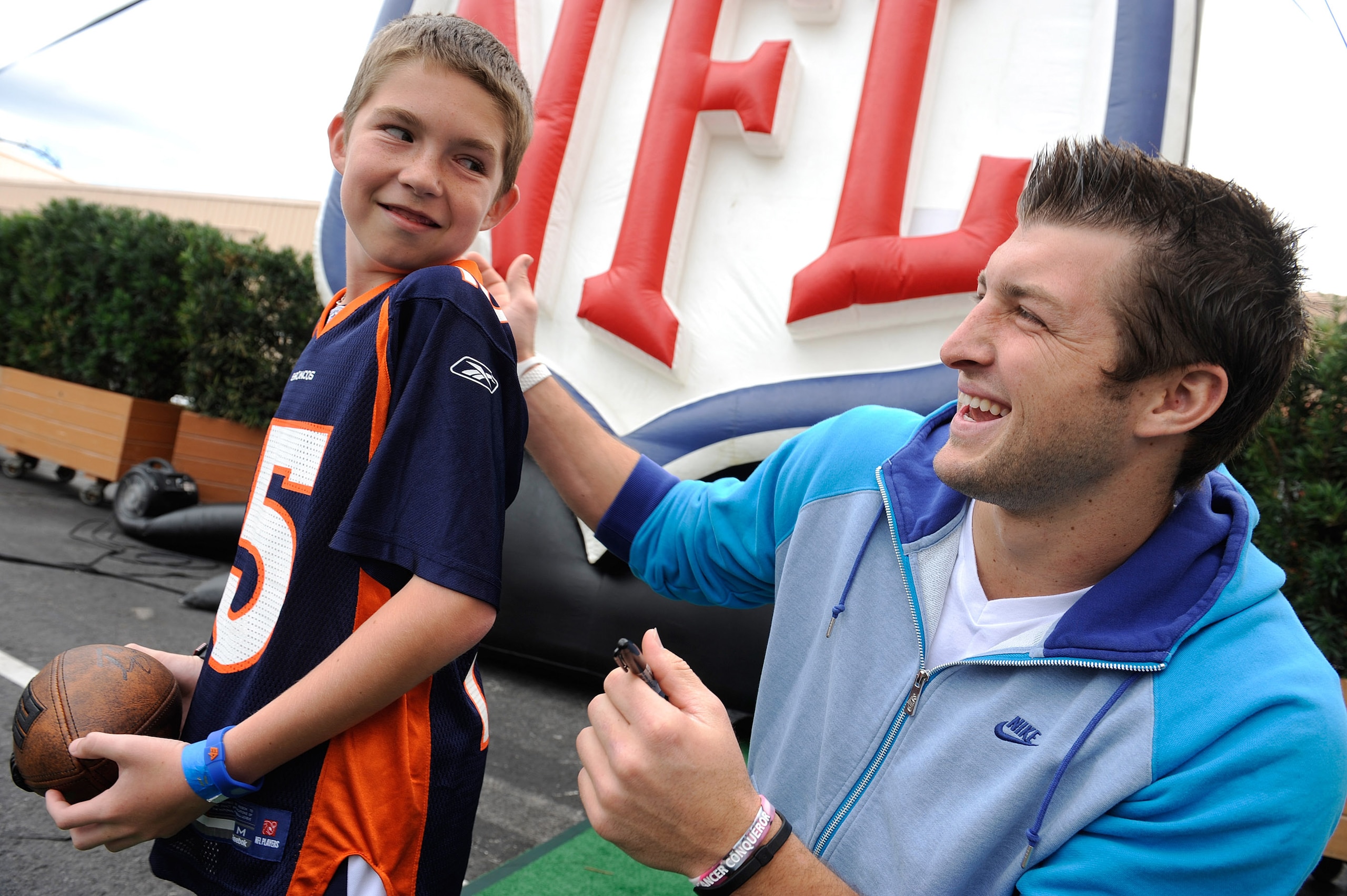 LAKE BUENA VISTA, FL - MAR 04: In this handout image provided by Disney Parks,  Denver Broncos quarterback Tim Tebow autographs a jersey for Cole Hoover, age 11, from Cape Coral, Florida at Disney's Hollywood Studios park in Lake Buena Vista, Florida on M