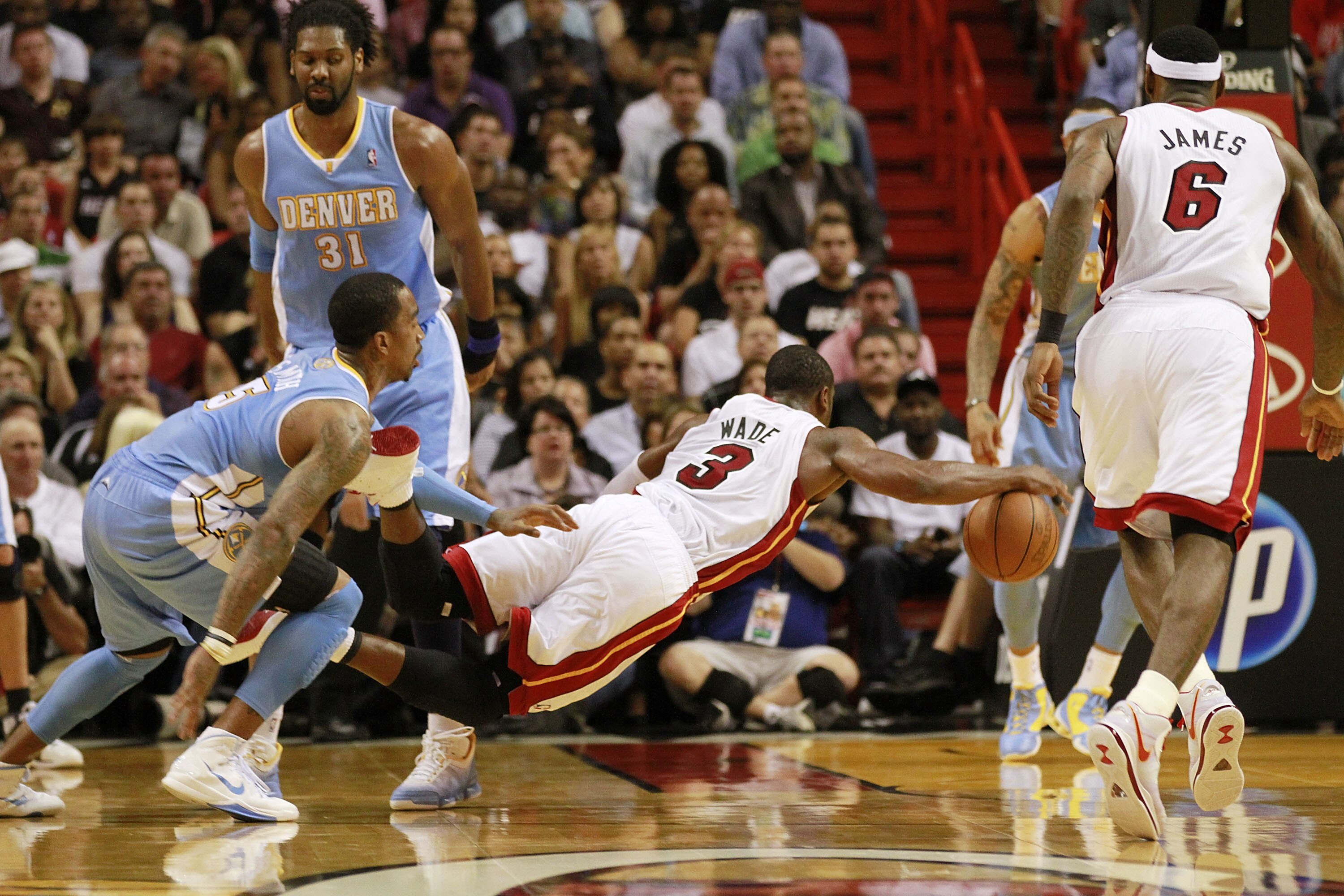 MIAMI, FL - MARCH 19:  Guard Dwyane Wade #3 of the Miami Heat is fouled by guard J.R. Smith (R) of the Denver Nuggets at American Airlines Arena on March 19, 2011 in Miami, Florida. The Heat defeated the Nuggets 103-98. NOTE TO USER: User expressly acknow