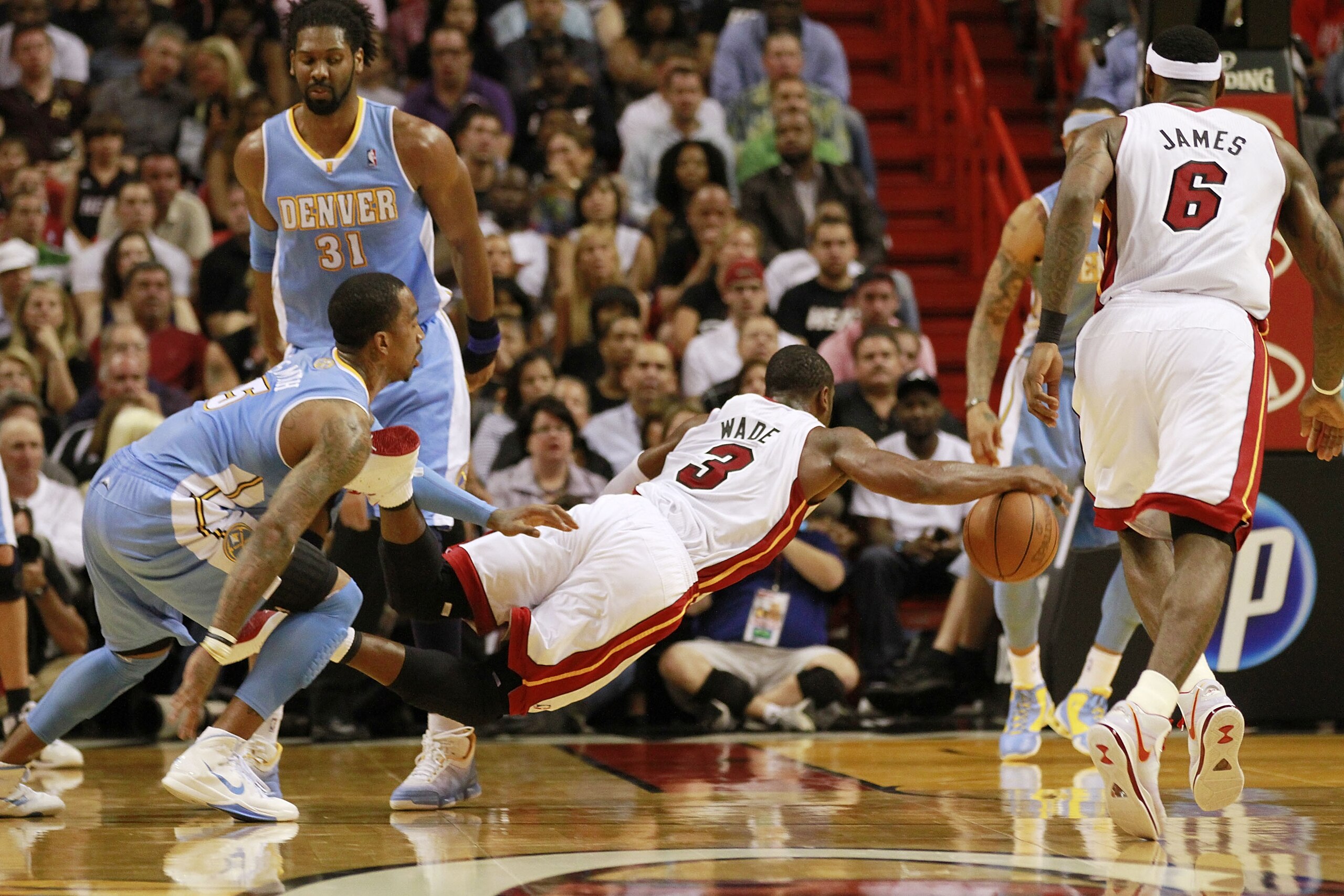 MIAMI, FL - MARCH 19:  Guard Dwyane Wade #3 of the Miami Heat is fouled by guard J.R. Smith (R) of the Denver Nuggets at American Airlines Arena on March 19, 2011 in Miami, Florida. The Heat defeated the Nuggets 103-98. NOTE TO USER: User expressly acknow