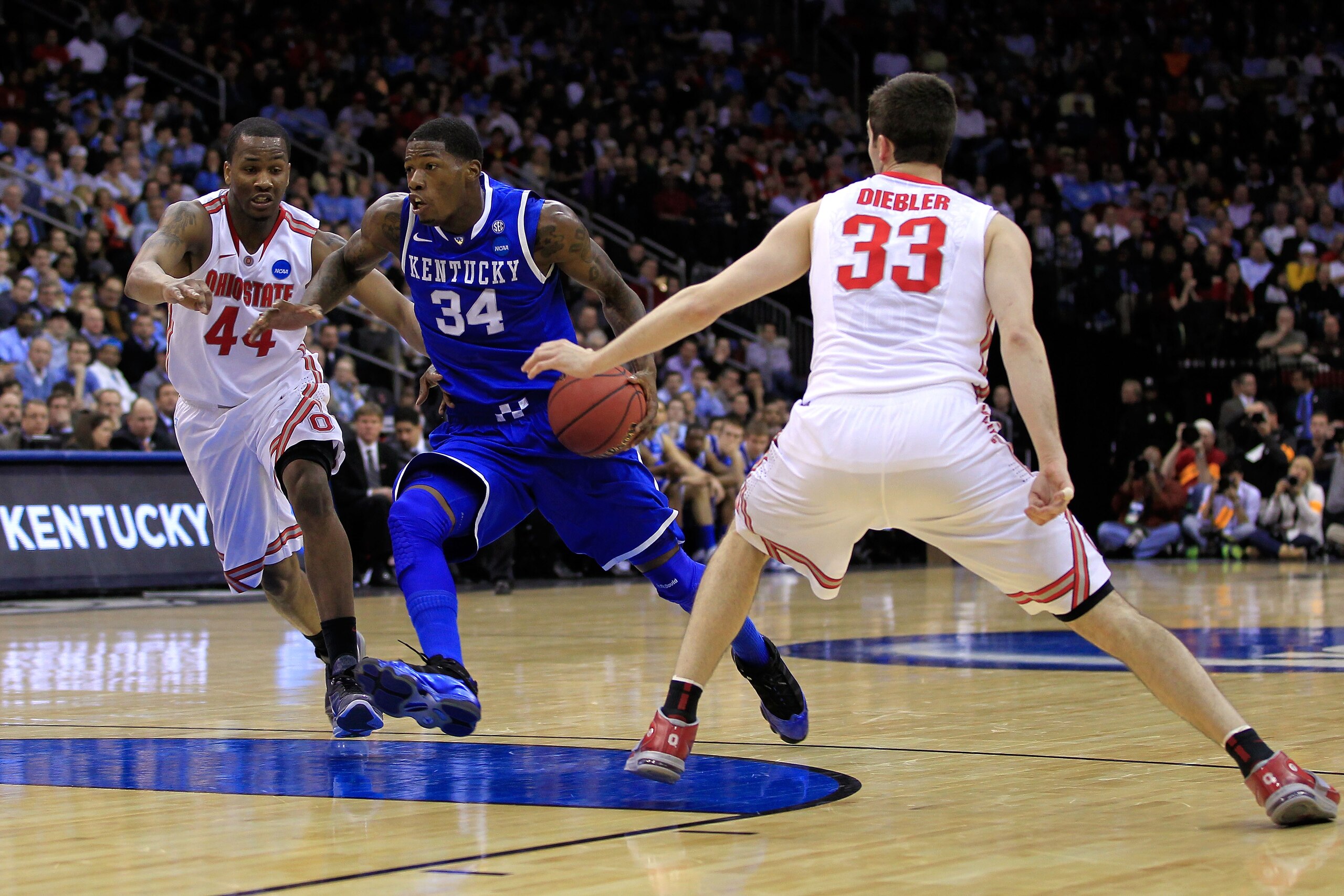 NEWARK, NJ - MARCH 25: DeAndre Liggins #34 of the Kentucky Wildcats drives against William Buford #44 and Jon Diebler #33 of the Ohio State Buckeyes during the first half of the east regional semifinal of the 2011 NCAA Men's Basketball Tournament at the NEWARK, NJ - MARCH 25: DeAndre Liggins #34 of the Kentucky Wildcats drives against William Buford #44 and Jon Diebler #33 of the Ohio State Buckeyes during the first half of the east regional semifinal of the 2011 NCAA Men's Basketball Tournament at the