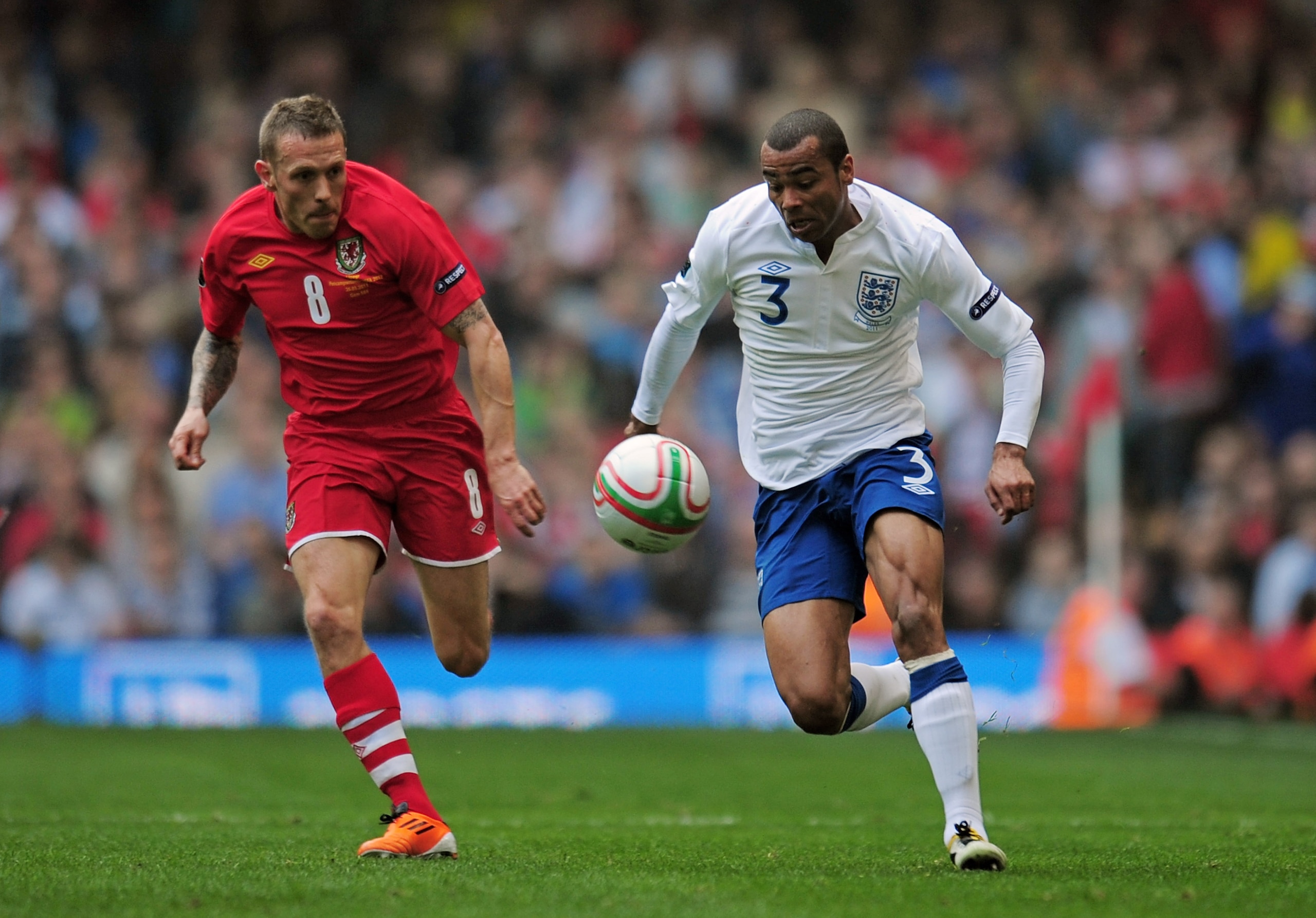 CARDIFF, WALES - MARCH 26:  Ashley Cole of England is pursued by Craig Bellamy of Wales during the UEFA EURO 2012 Group G qualifying match between Wales and England at the Millennium Stadium on March 26, 2011 in Cardiff, Wales.  (Photo by Shaun Botterill/