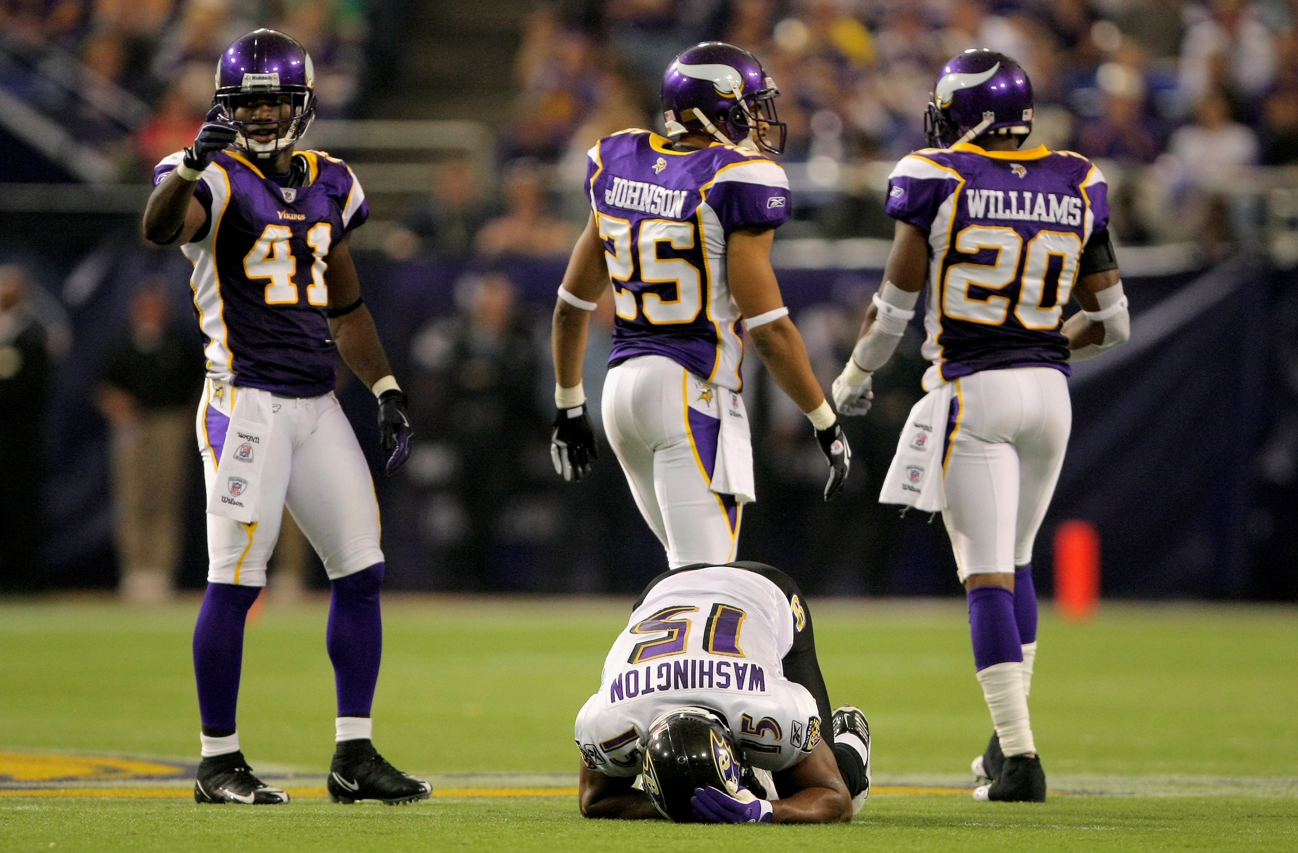 MINNEAPOLIS - OCTOBER 18:  Wide reciever Kelley Washington #15 of the Baltimore Ravens is shaken up after making a reception as Karl Paymah #41, Tyrell Johnson #25 and Madieu Williams #20 of the Minnesota Vikings walk away after the play during NFL action