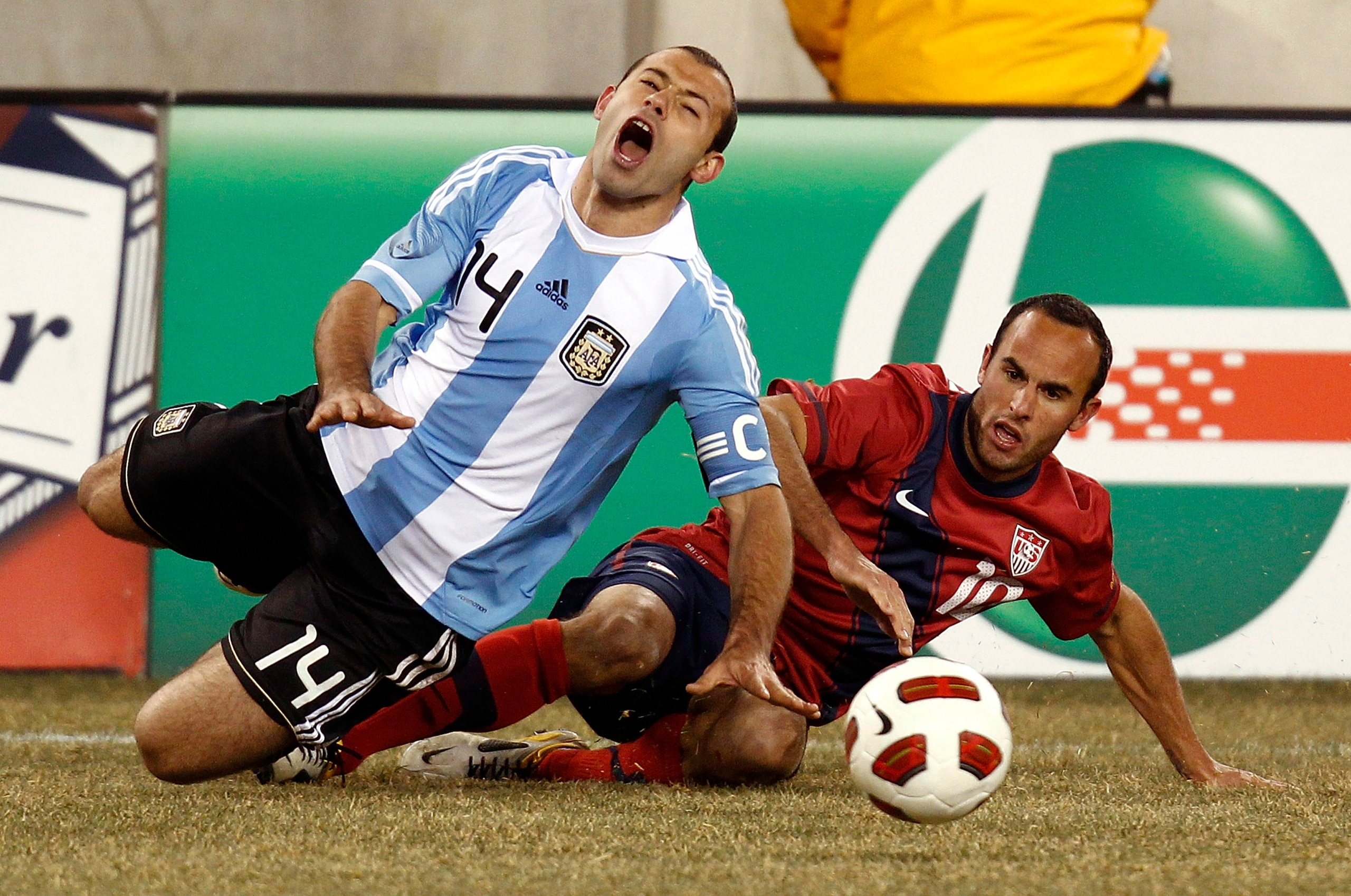 EAST RUTHERFORD, NJ - MARCH 26:  Javier Mascherano #14 of Argentina falls to the turf on front of Landon Donovan #10 of the United States during the second half of a friendly match at New Meadowlands Stadium on March 26, 2011 in East Rutherford, New Jerse