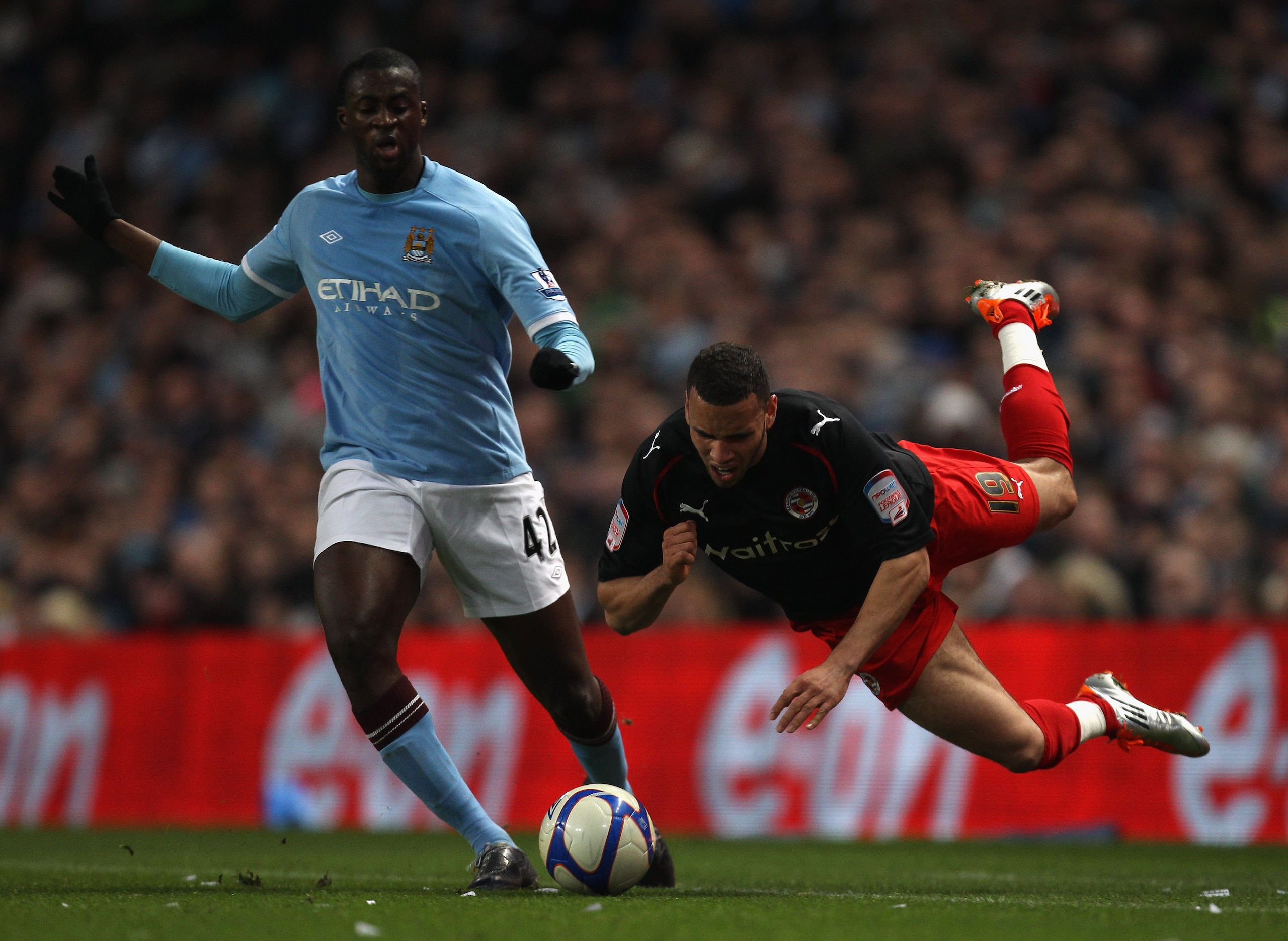 MANCHESTER, ENGLAND - MARCH 13:  Hal Robson-Kanu of Reading falls under the challenge of Yaya Toure of Manchester City during the FA Cup sponsored by E.On Sixth Round match between Manchester City and Reading at the City of Manchester Stadium on March 13,