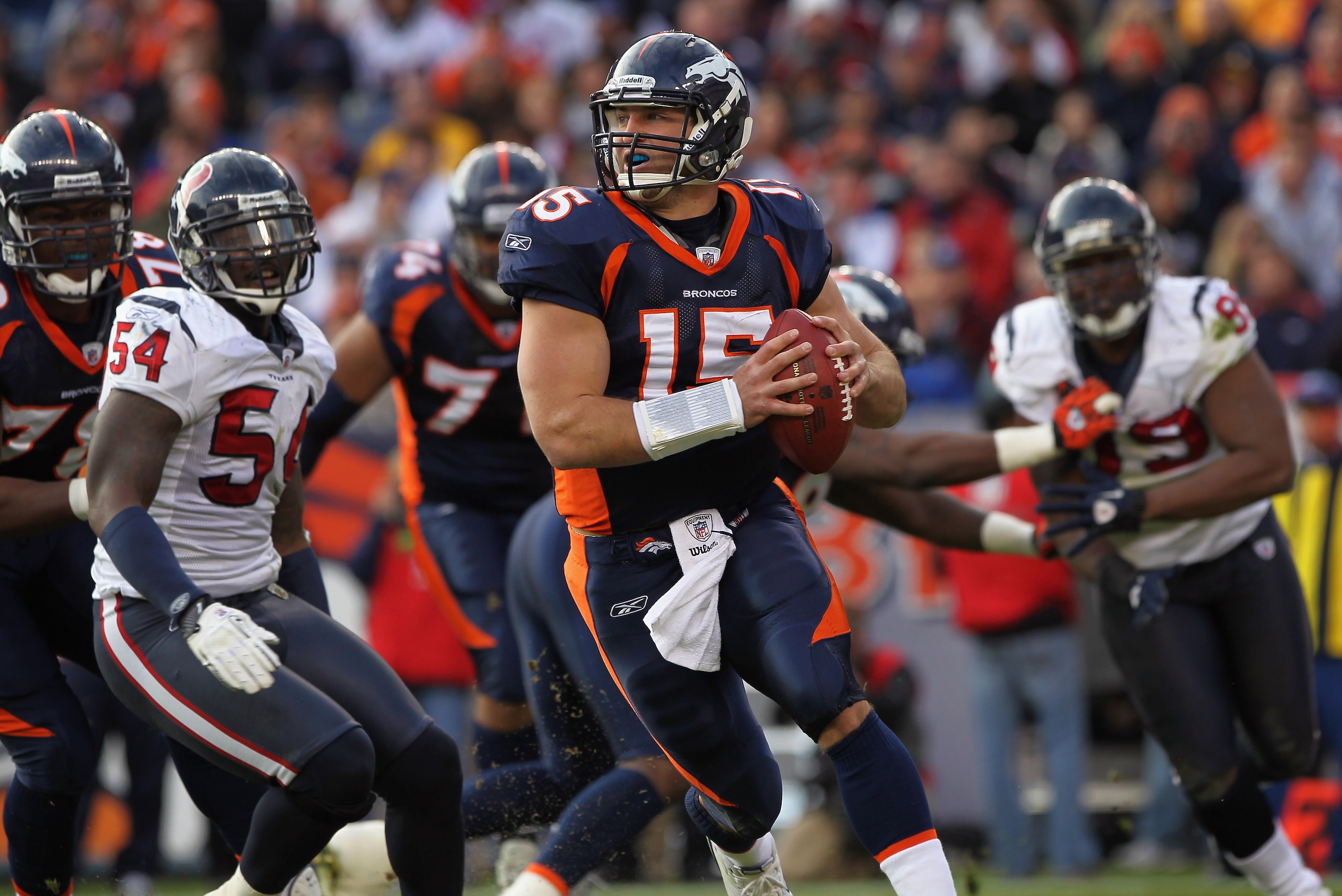 DENVER - DECEMBER 26:  Quarterback Tim Tebow #15 of the Denver Broncos rolls out and looks to deliver a pass against the Houston Texas at INVESCO Field at Mile High on December 26, 2010 in Denver, Colorado. The Broncos defeated the Texans 24-23.  (Photo b