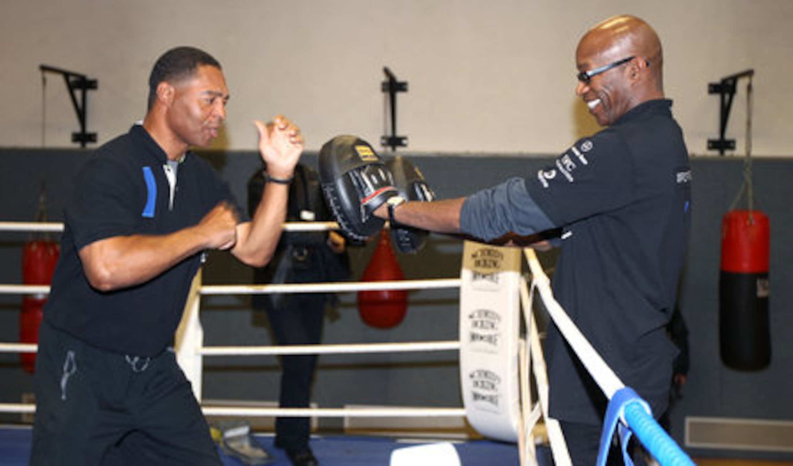 Marcus Allen spars with track legend Edwin Moses in Berlin.
