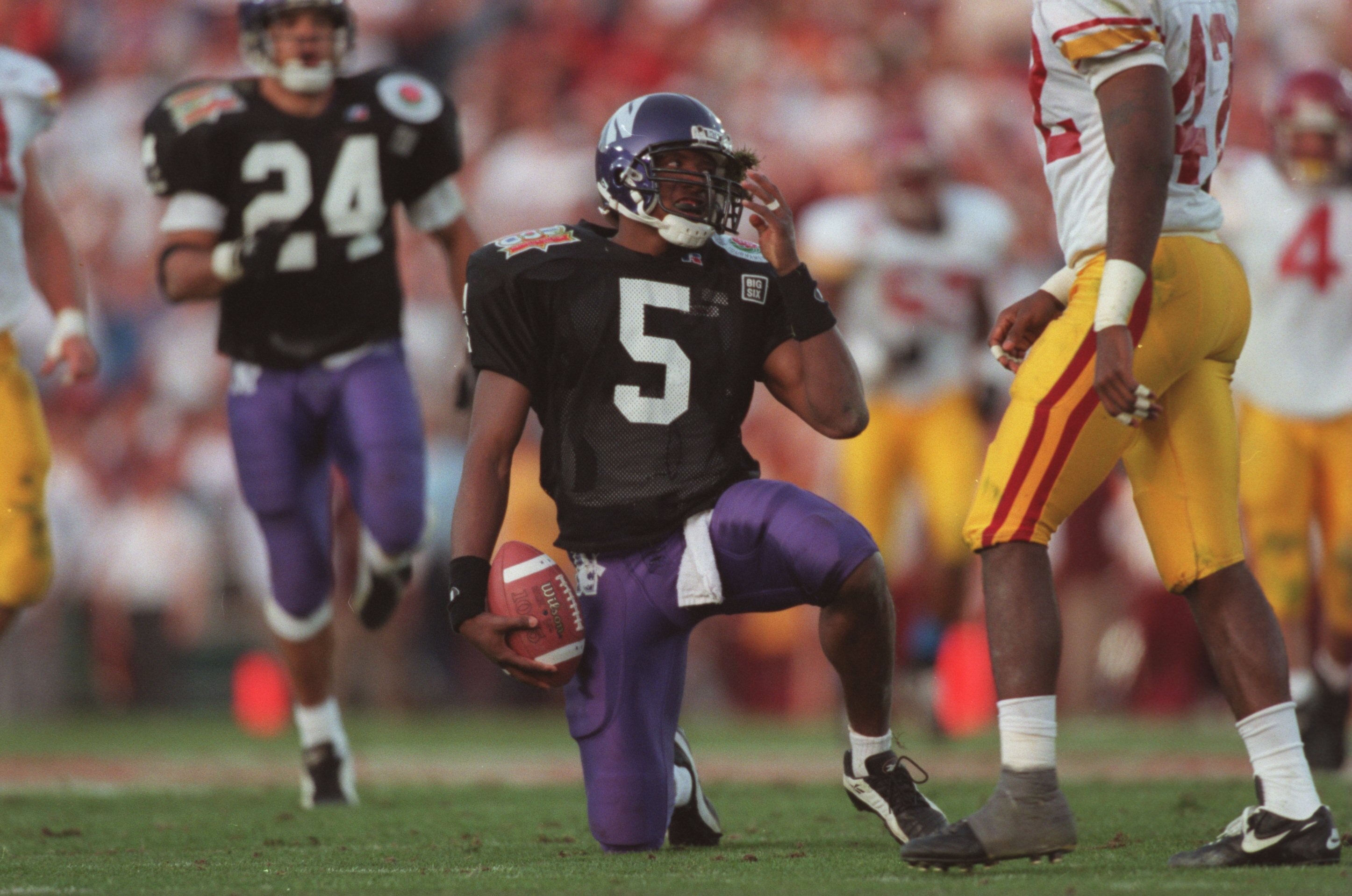 1 Jan 1996:  Running back D'Wayne Bates #5 of the Northwestern Wildcats reaches for his helmet as he attempts to remove a clump of grass from his face mask following a carry in the Wildcats 41-32 loss to the USC Trojans in the 1996 Rose Bowl game held at