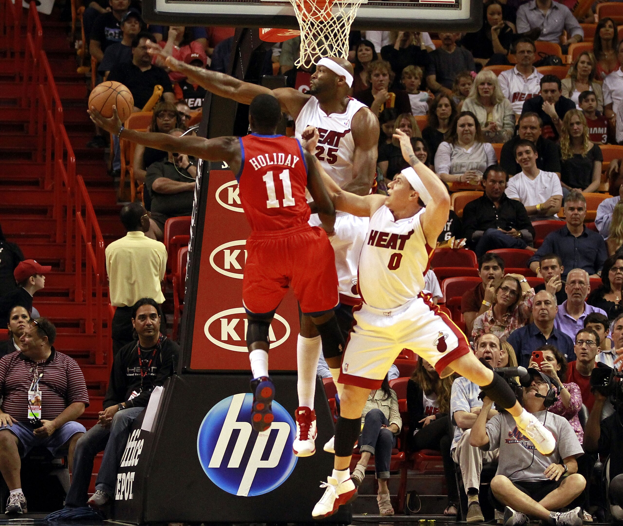 MIAMI, FL - MARCH 25:  Center Erick Dampier #25 and guard Mike Bibby #0 of the Miami Heat defend against Forward Jrue Holiday #11 of the Philadelphia 76ers at American Airlines Arena on March 25, 2011 in Miami, Florida. The Heat defeated the Sixers 111-99
