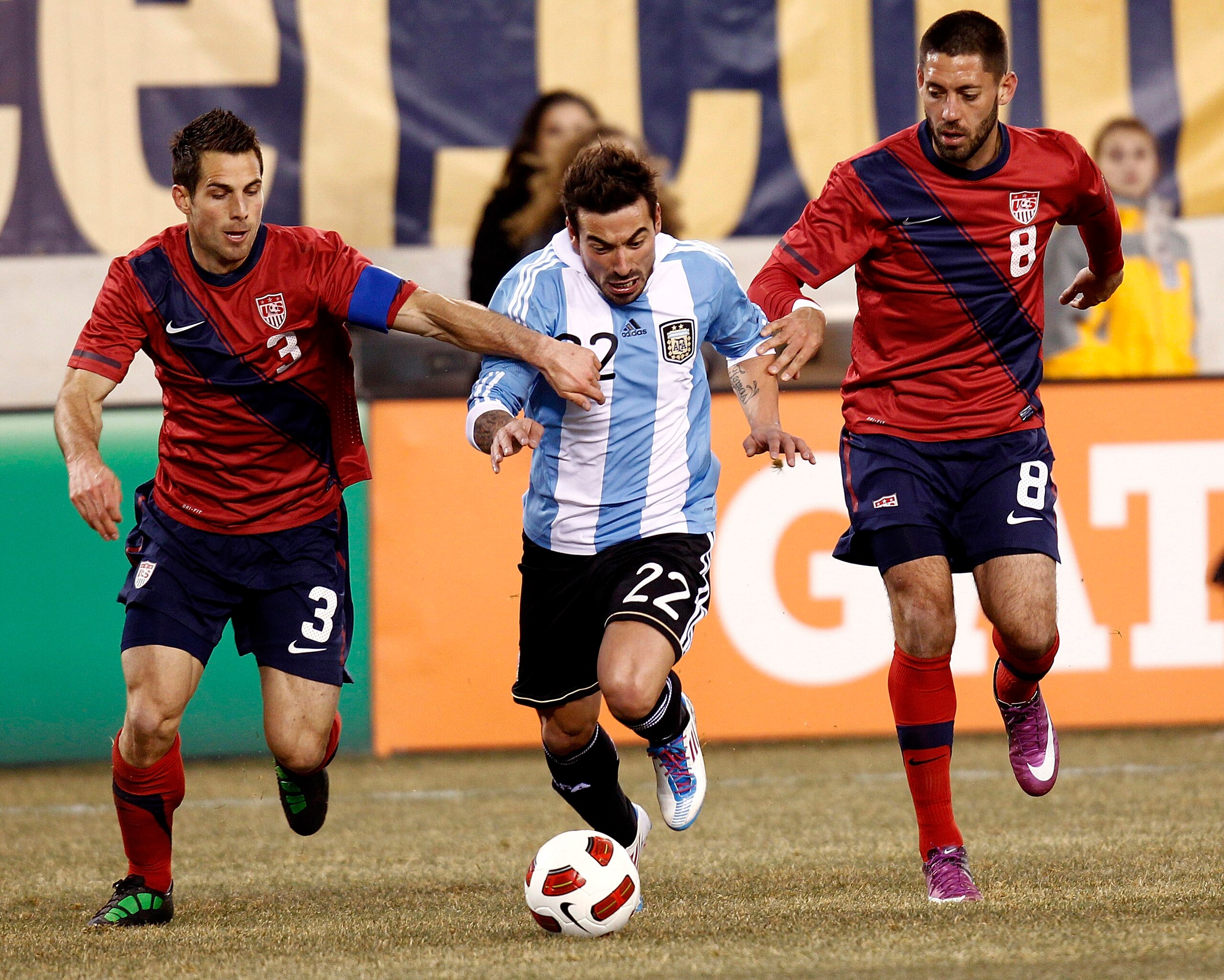 EAST RUTHERFORD, NJ - MARCH 26:  Ezequiel Lavezzi #22 of Argentina dribbles between Carlos Bocanegra #3 and Clint Dempsey #8 of the United States during the first half of a friendly match at New Meadowlands Stadium on March 26, 2011 in East Rutherford, Ne